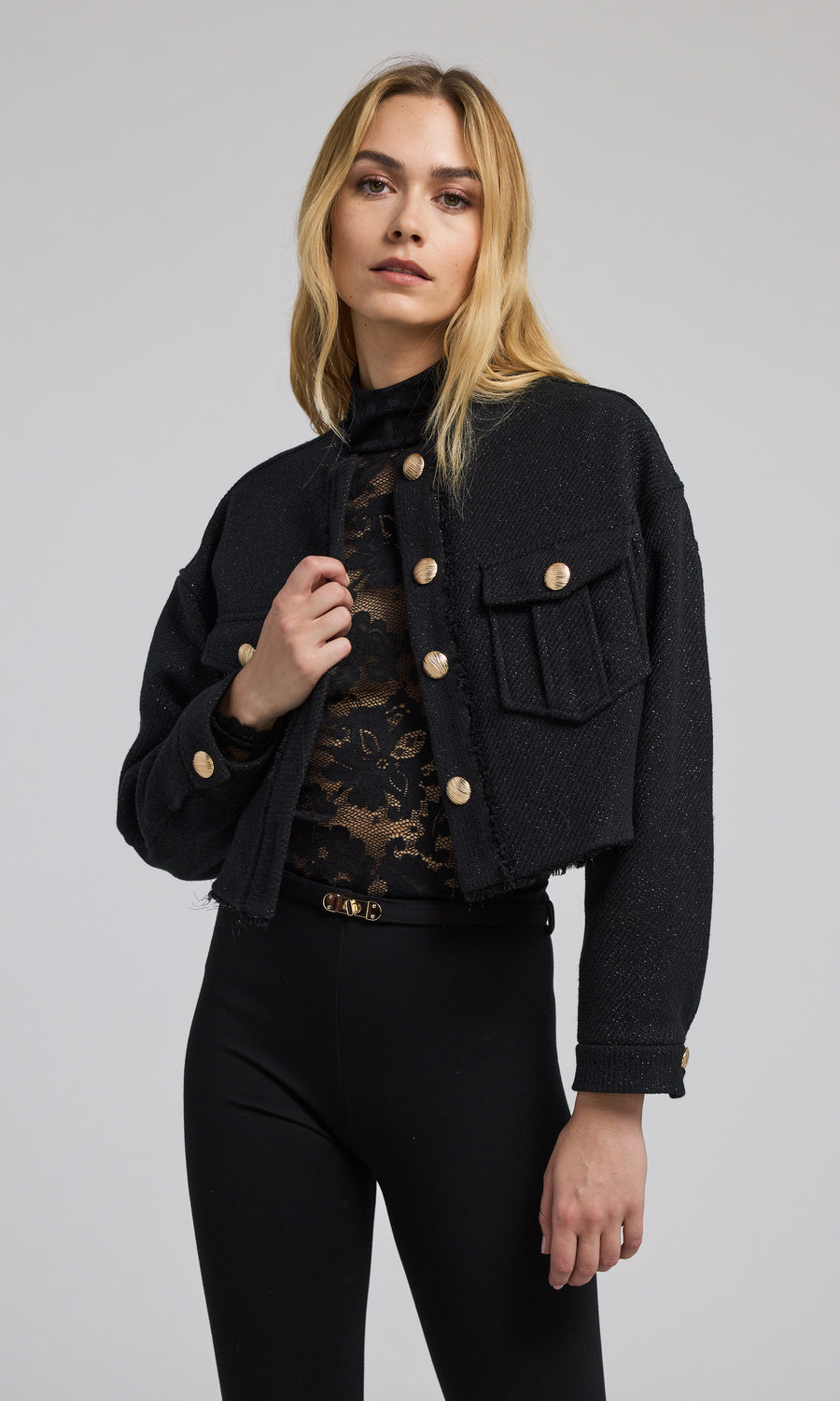 A stylish black cropped bomber jacket with gold buttons, emphasizing a modern and elegant look in outerwear fashion.