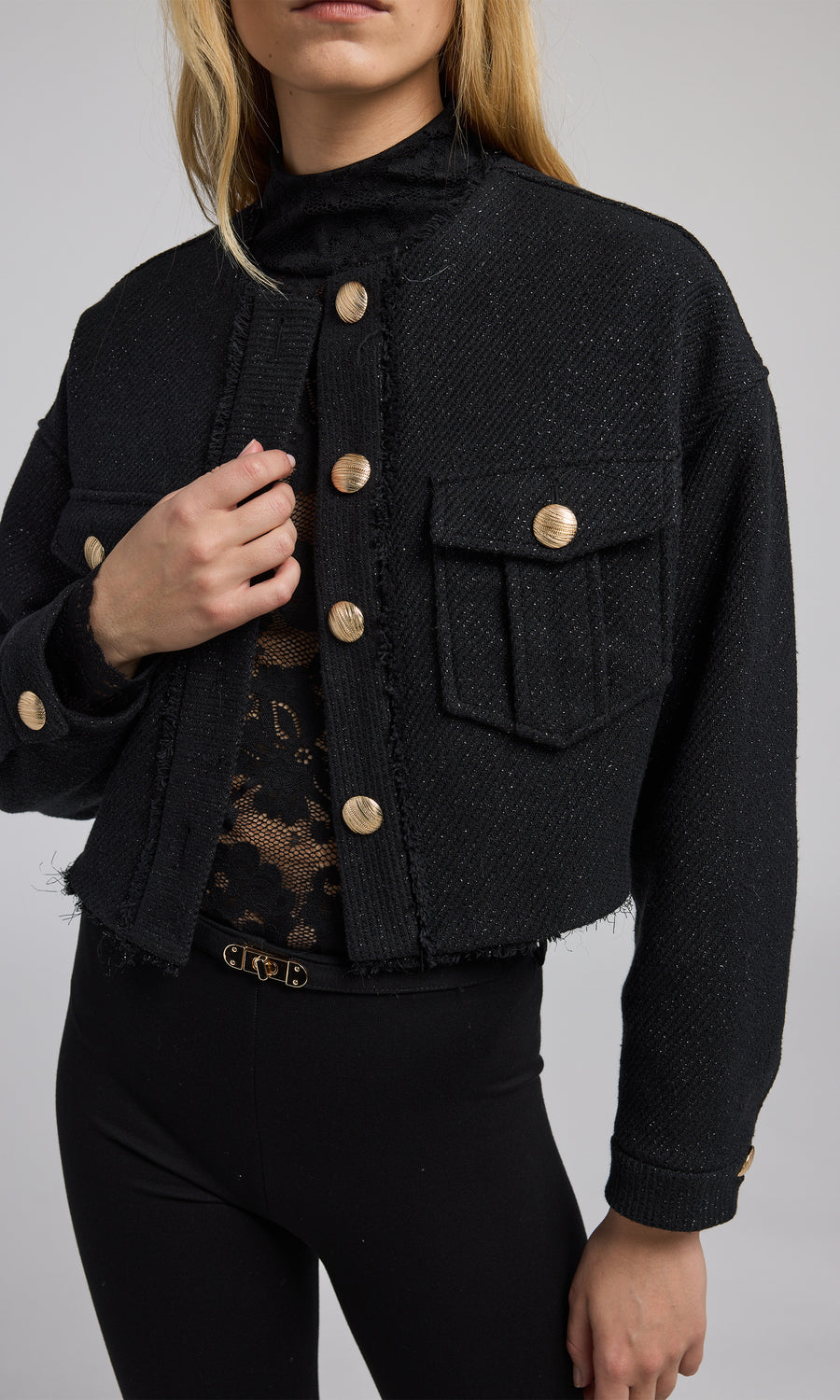 A stylish black cropped bomber jacket with gold buttons, emphasizing a modern and elegant look in outerwear fashion.