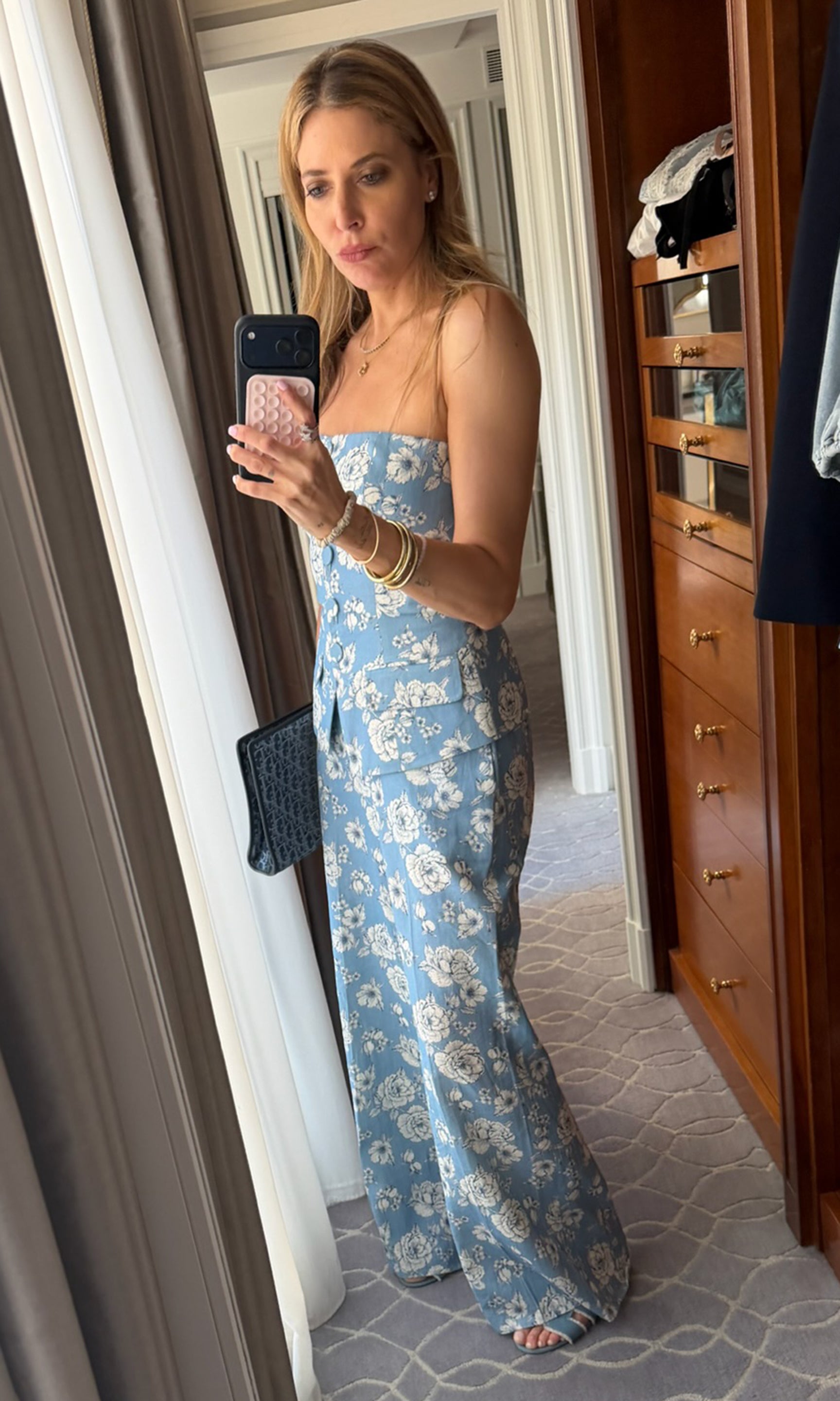 Our founder, Roni, taking a mirror selfie wearing a blue floral strapless set in a room with wooden furniture.