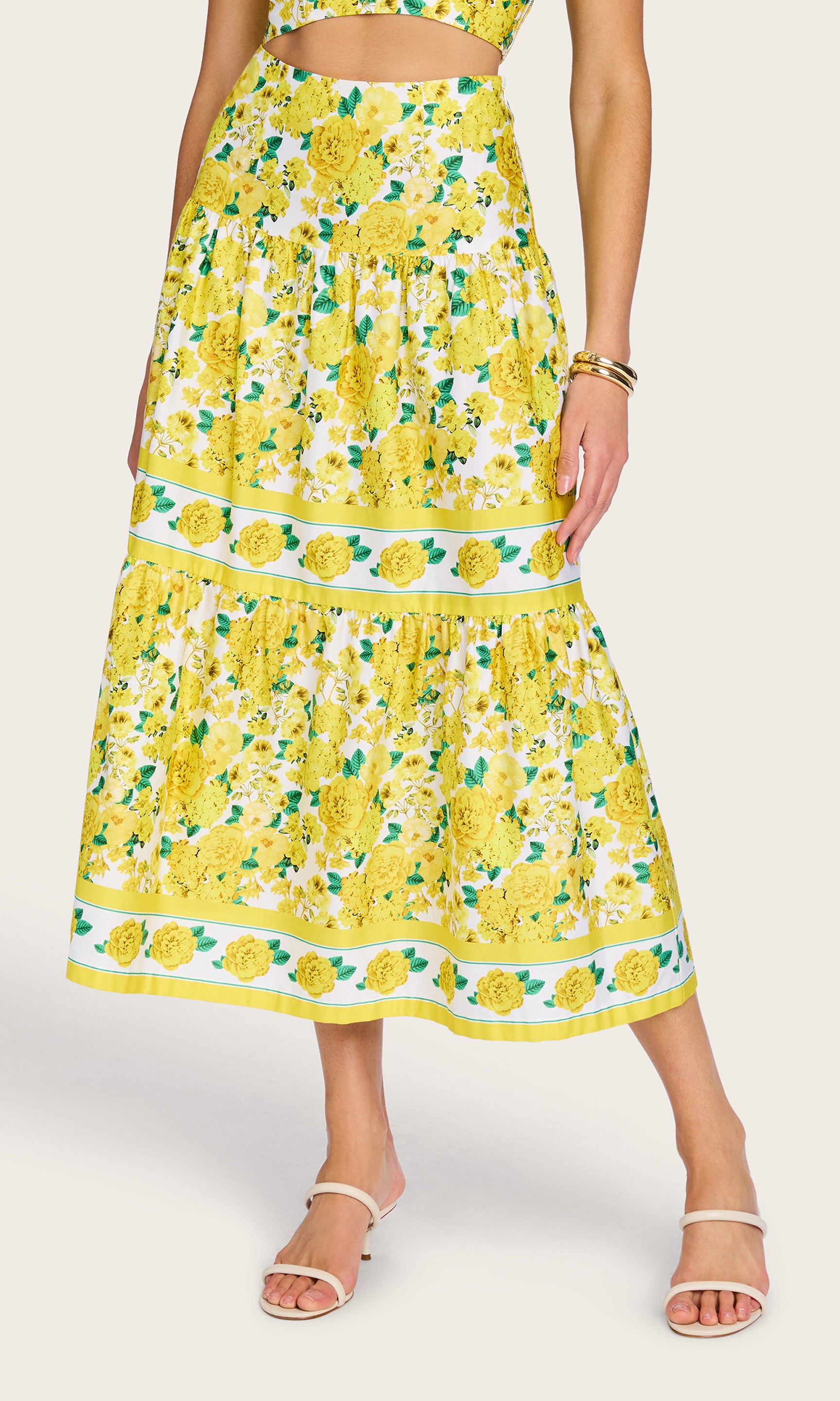 Front view of the model wearing the Mondo Floral Poplin Skirt in a yellow floral print with the matching floral bra top, highlighting the tiered structure and bright summer print.