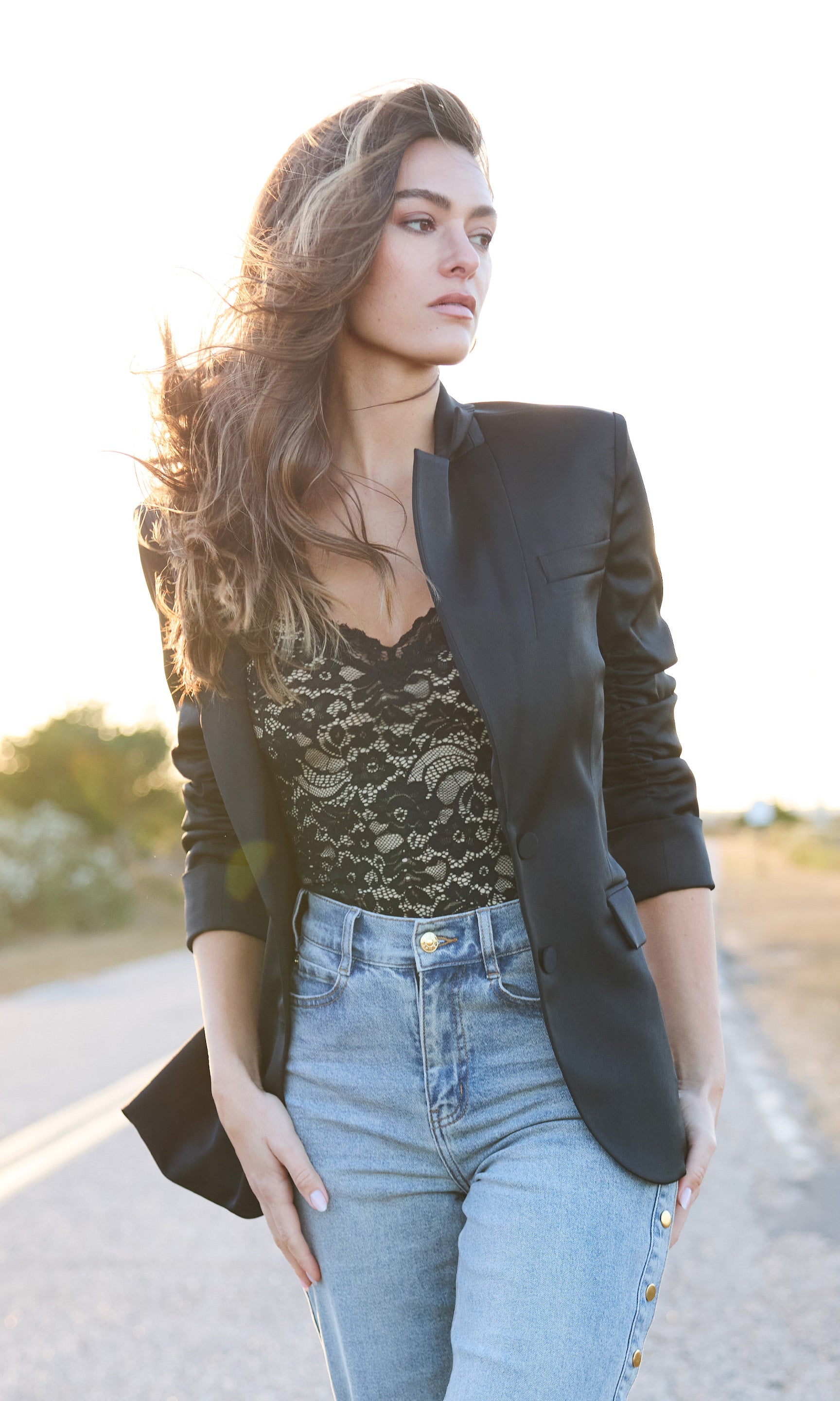 woman wearing black satin blazer with black lace bodysuit and denim