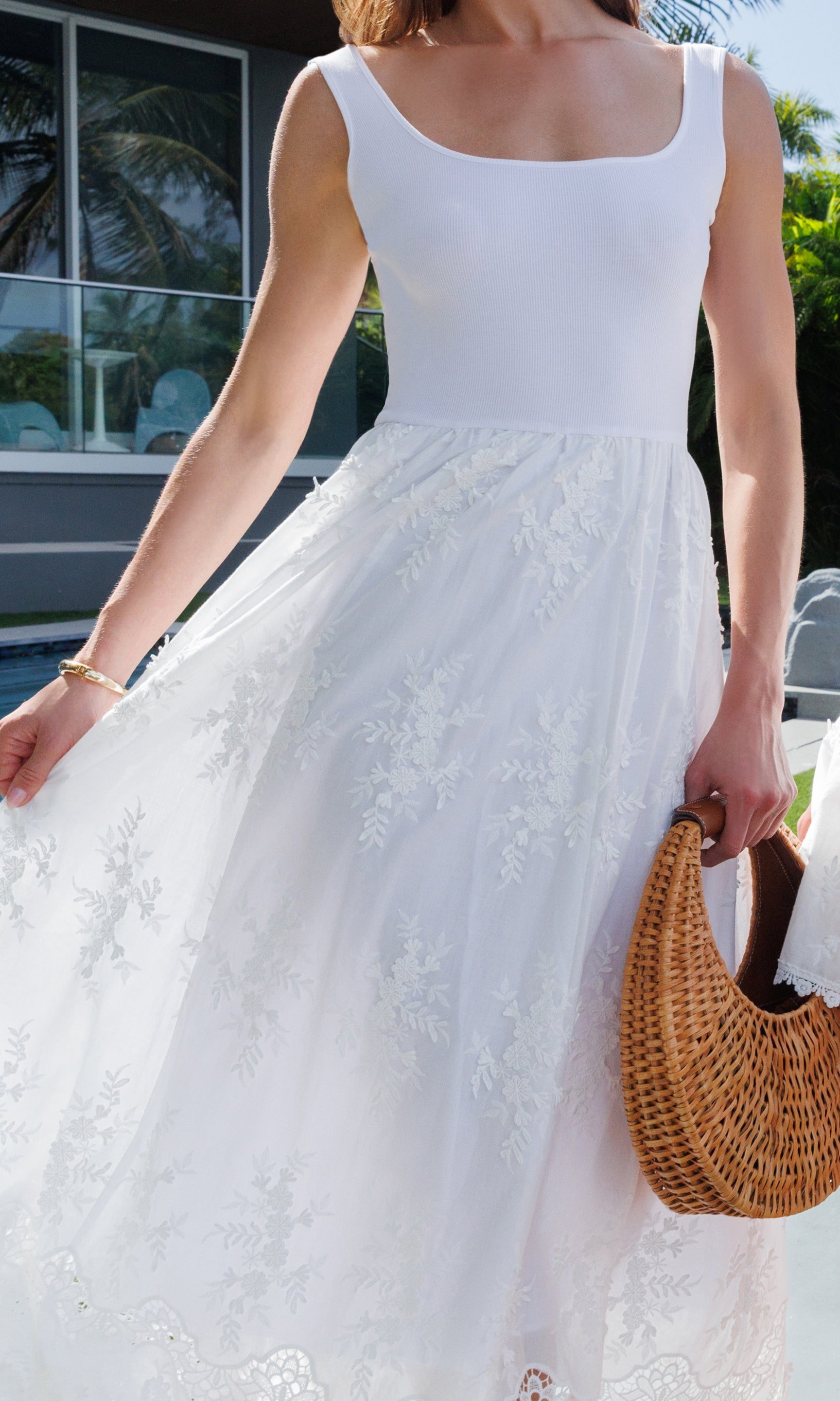 Woman in a white dress holding a woven bag outdoors