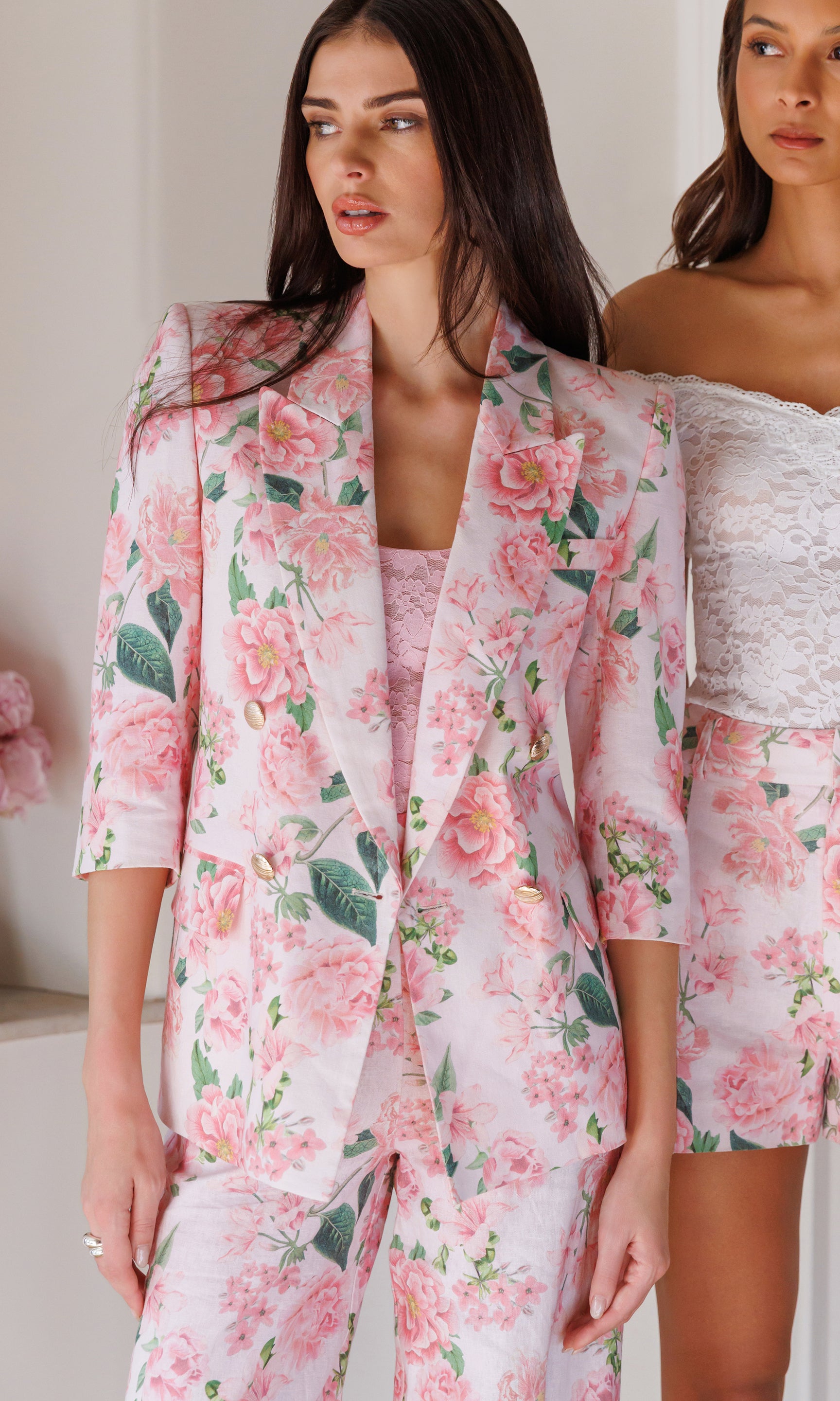 Woman wearing a floral blazer and matching pants in an indoor setting