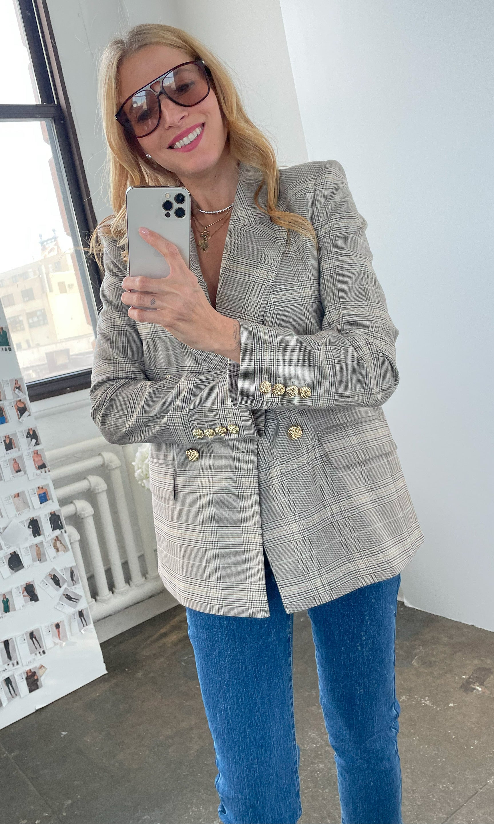 Our founder Roni wearing a gray checkered blazer and blue jeans indoors.