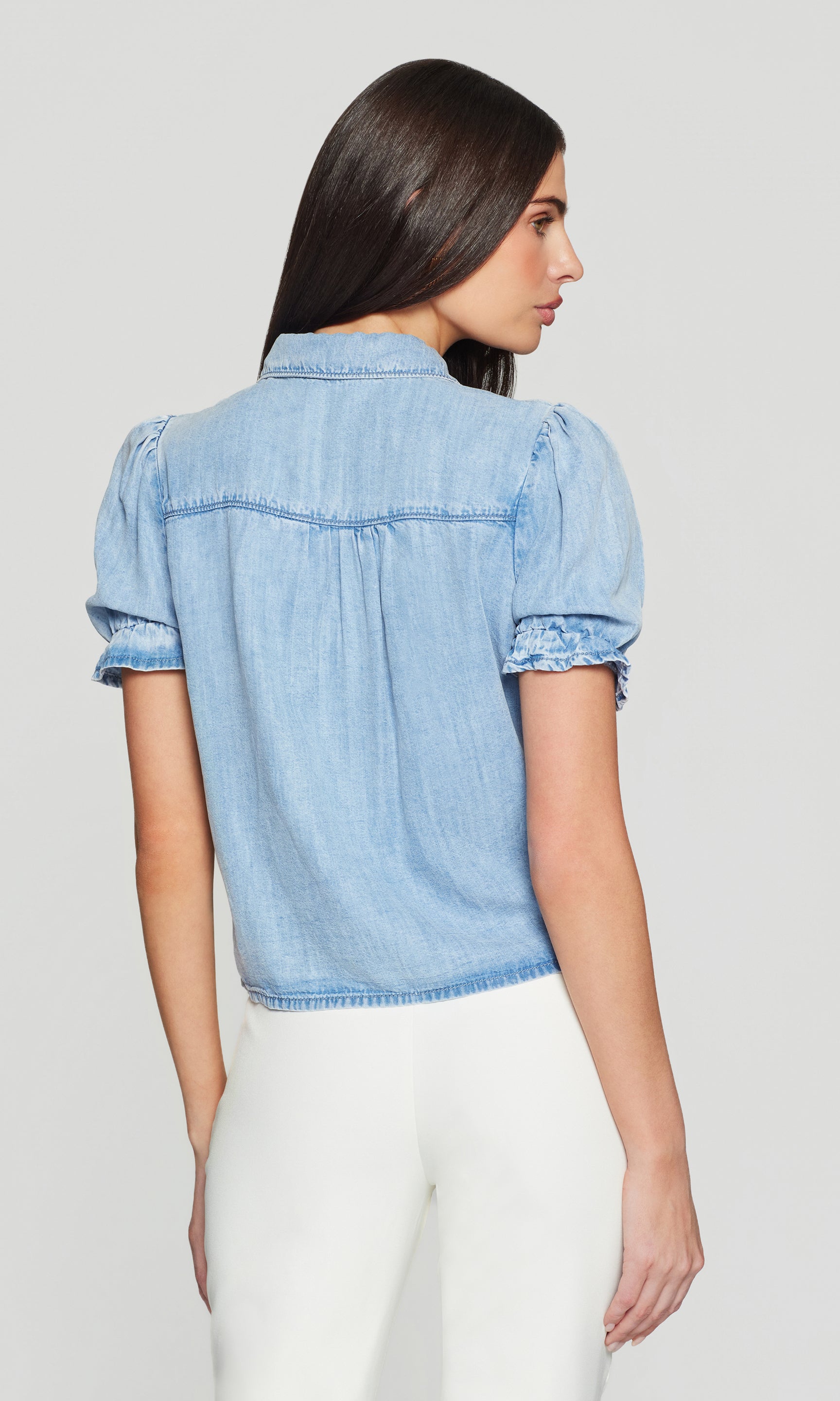 Back view of model wearing a short sleeve denim top and white pants