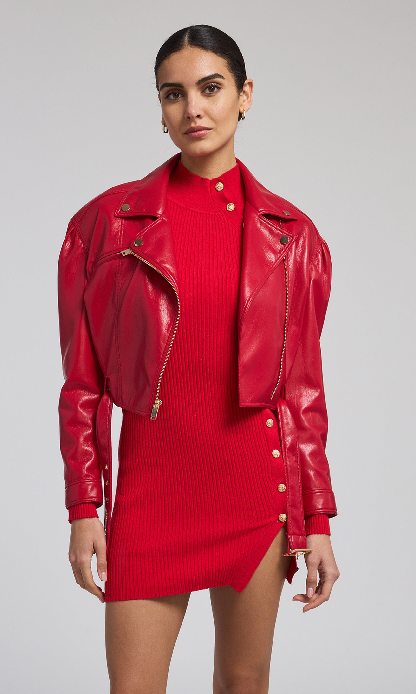 A striking red vegan leather jacket worn by the model emphasizes a modern and edgy aesthetic in her overall look.