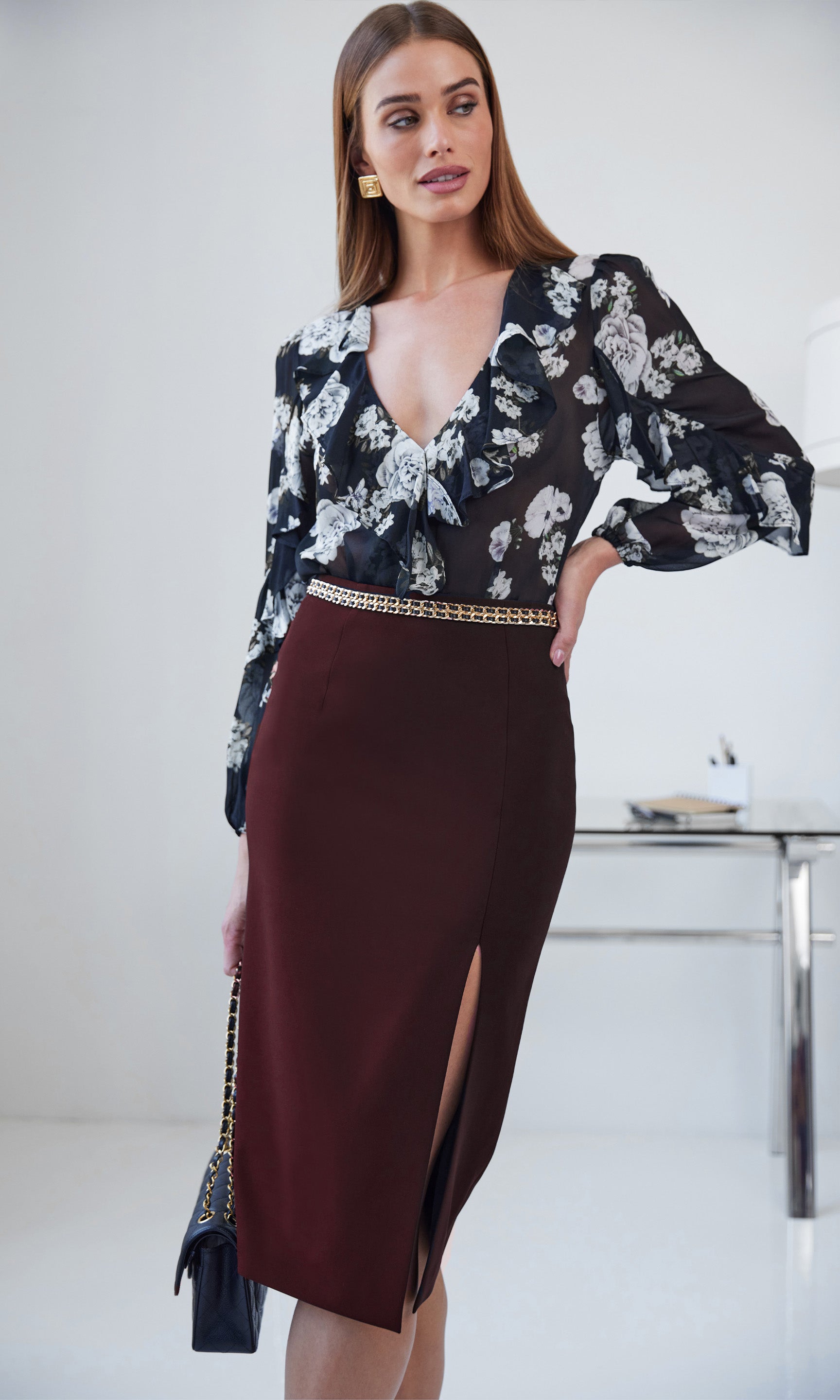 women wearing Malbec colored skirt with chain detailing and holding a black bag