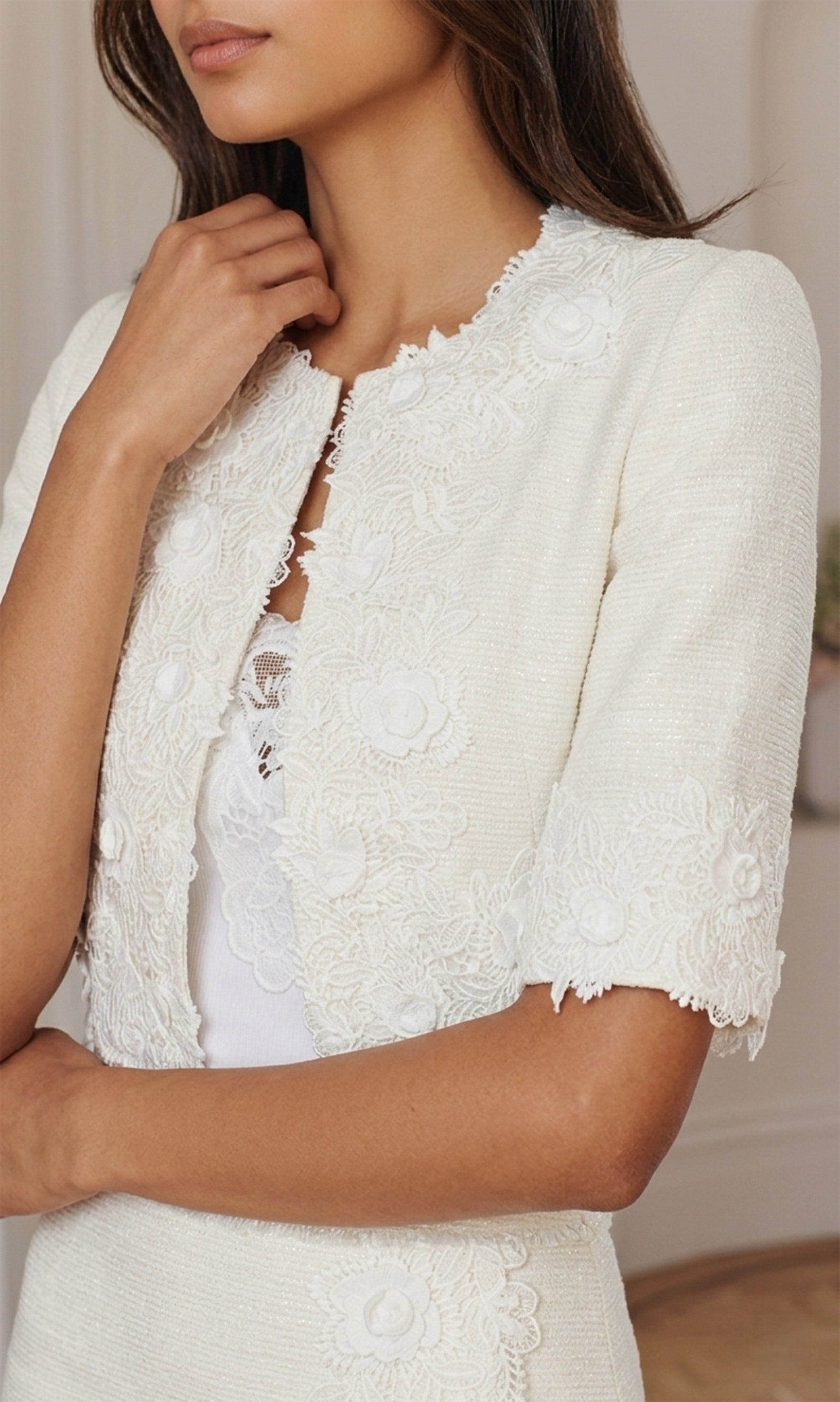 White lace shrug worn over a white top with a neutral background