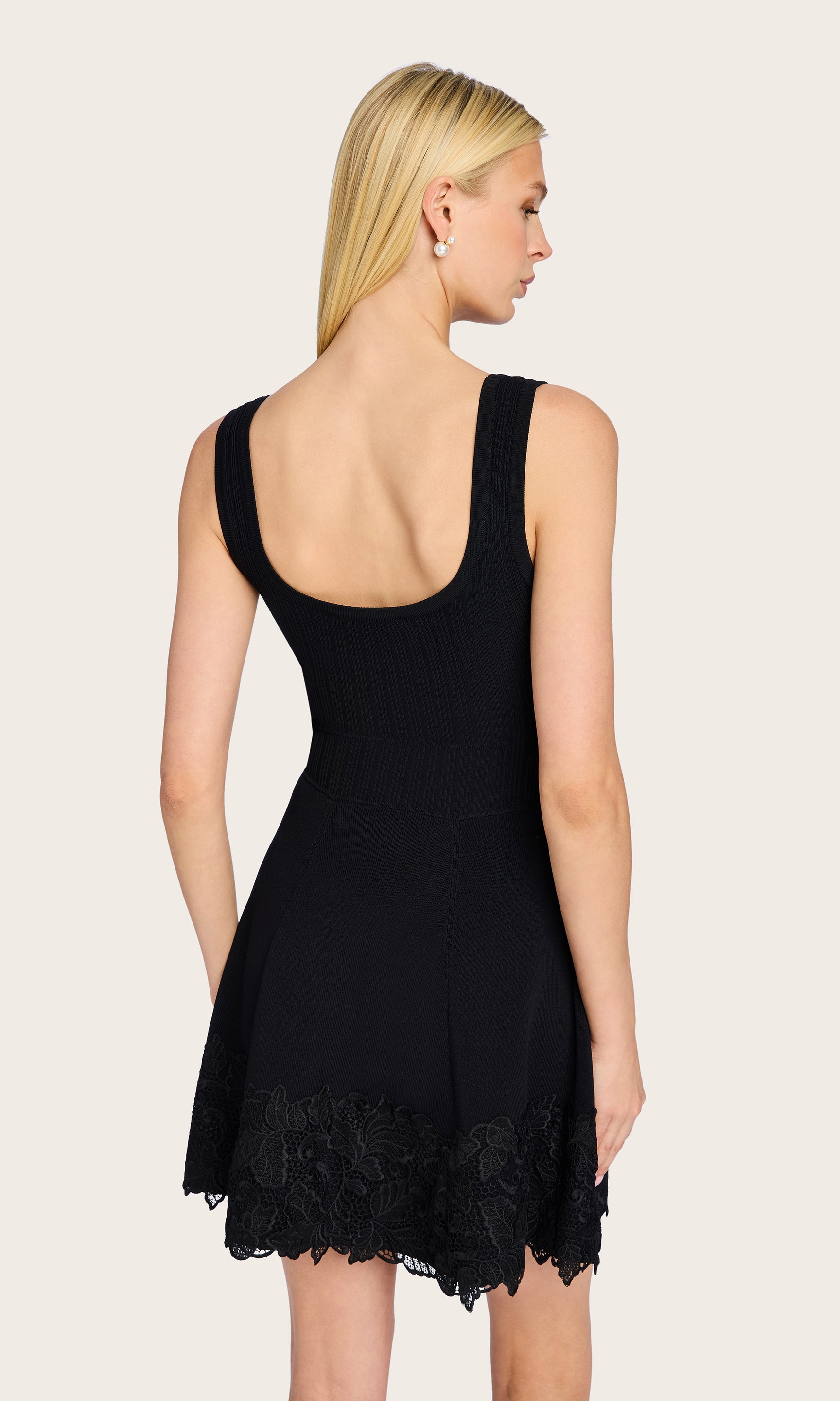Rear view of the model wearing the Orpheus Lace Combo Rib Dress, highlighting the scoop back and the flared hemline with lace trim.