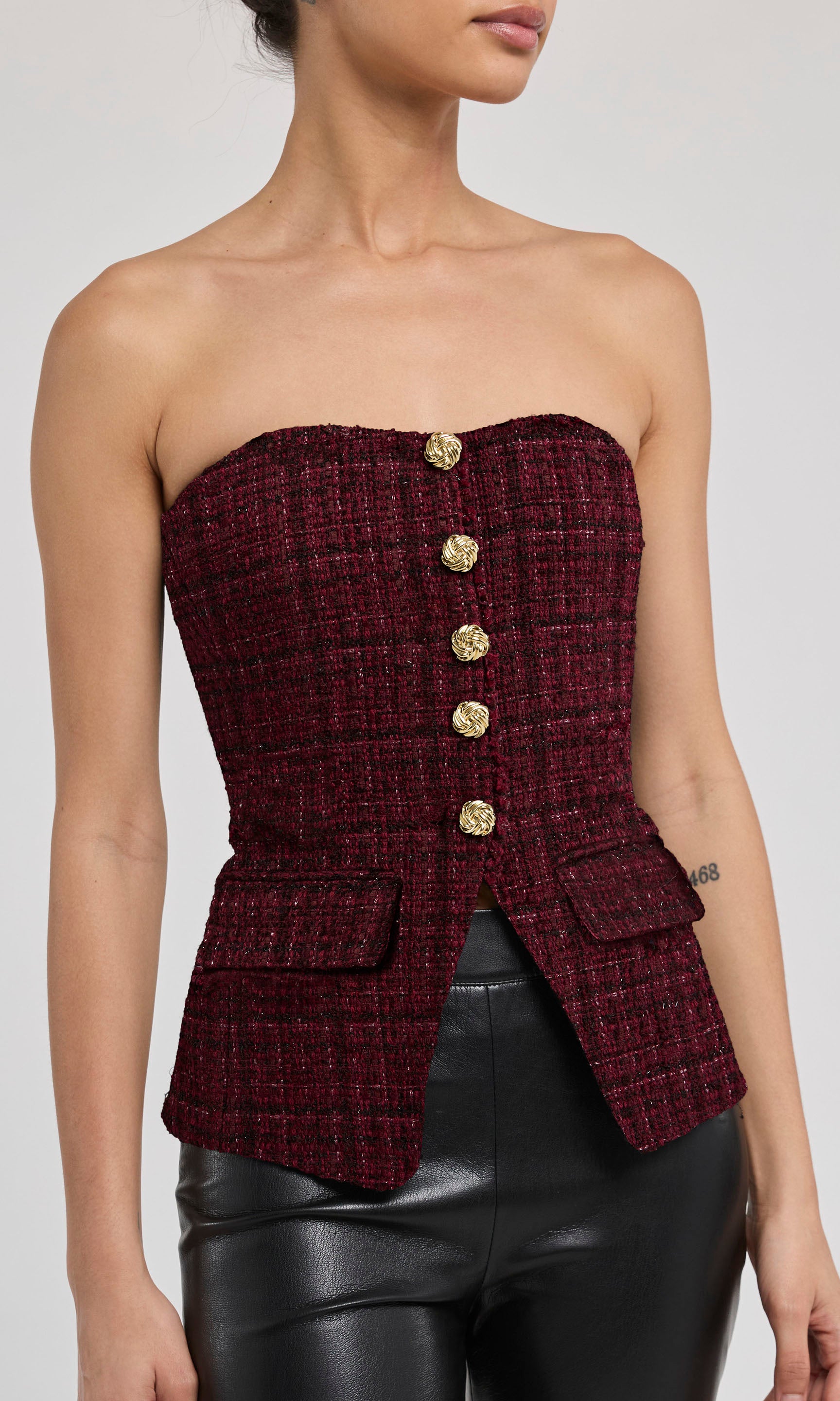 Maroon strapless tweed top with gold buttons on a plain background