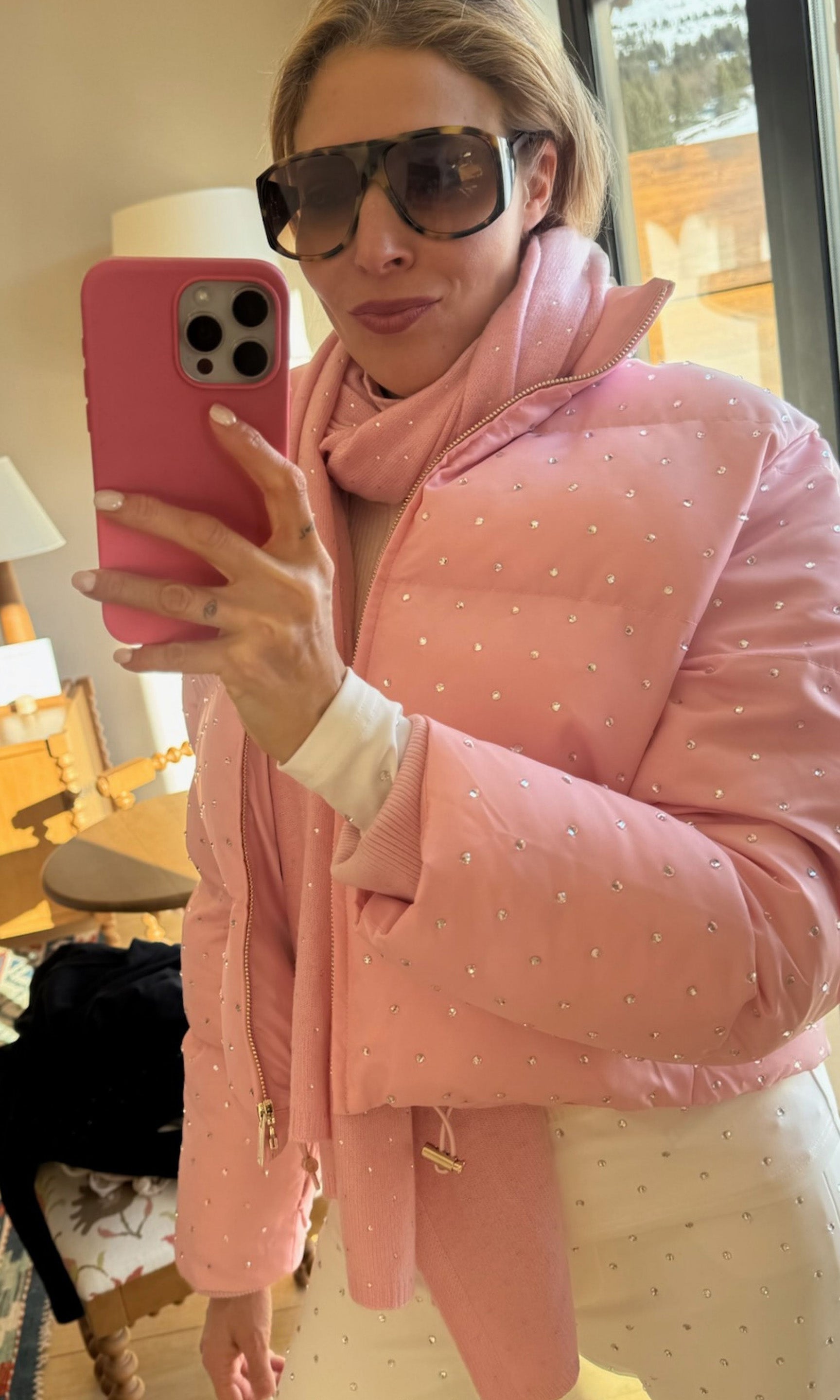 Person wearing a pink crystal embellished outfit with sunglasses, holding a pink phone.