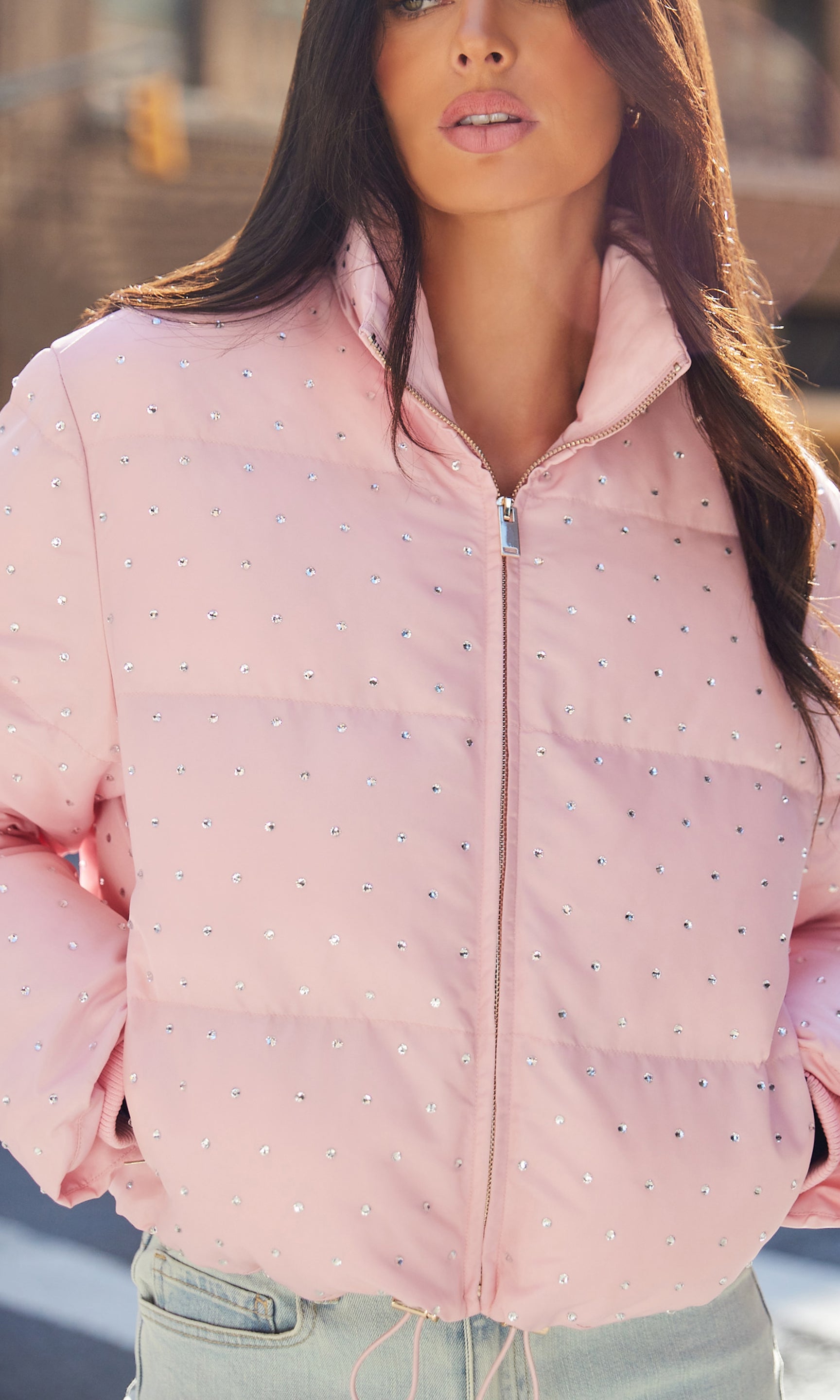 Person wearing a pink puffer jacket with a pattern, standing outdoors.