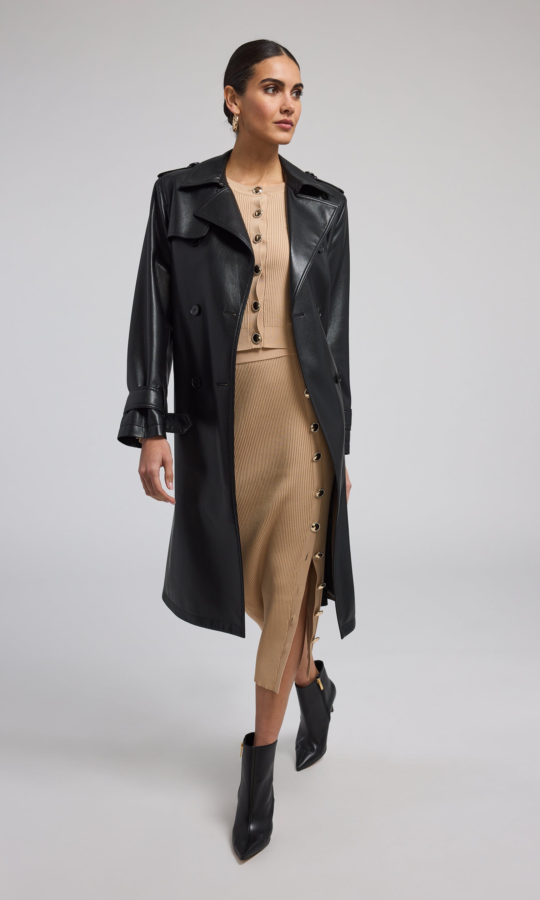 A model showcases a stylish black vegan leather trench coat, exuding elegance and modern sophistication.