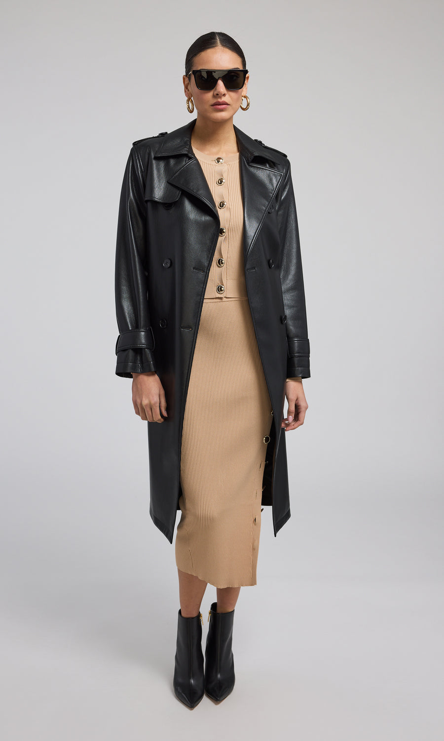 A model showcases a stylish black vegan leather trench coat, exuding elegance and modern sophistication.