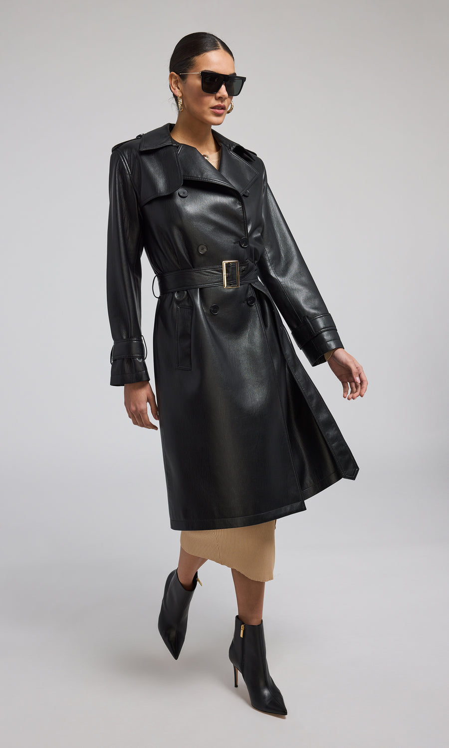 A model showcases a stylish black vegan leather trench coat, exuding elegance and modern sophistication.