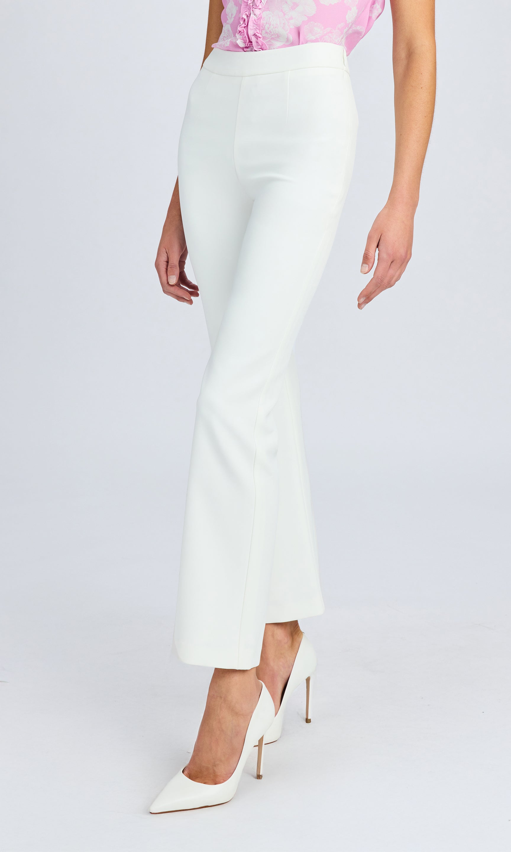 Side view of the white high-waisted pants, styled with a pink top.