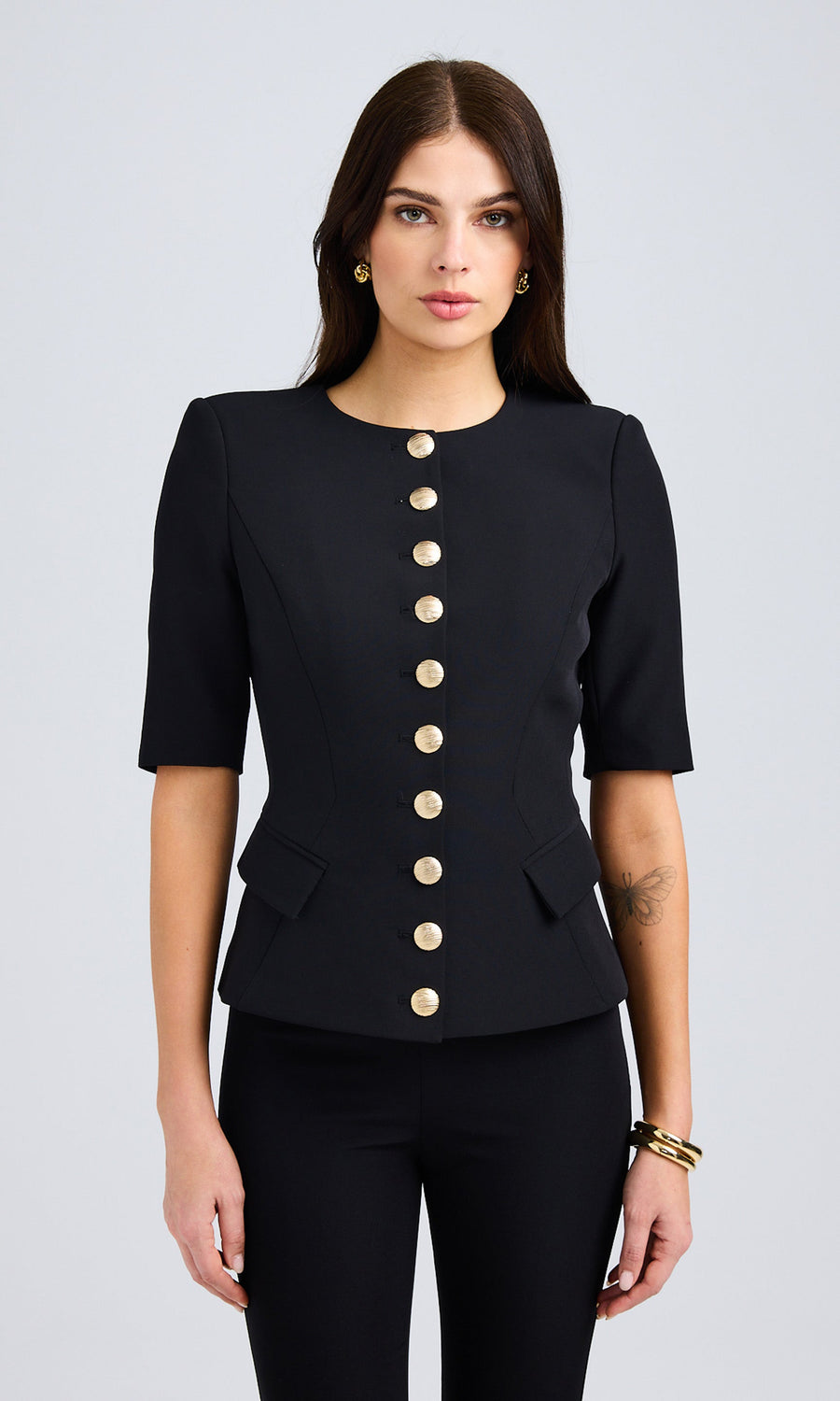 Model wearing a lightweight black jacket with gold buttons, highlighting its chic and modern look.