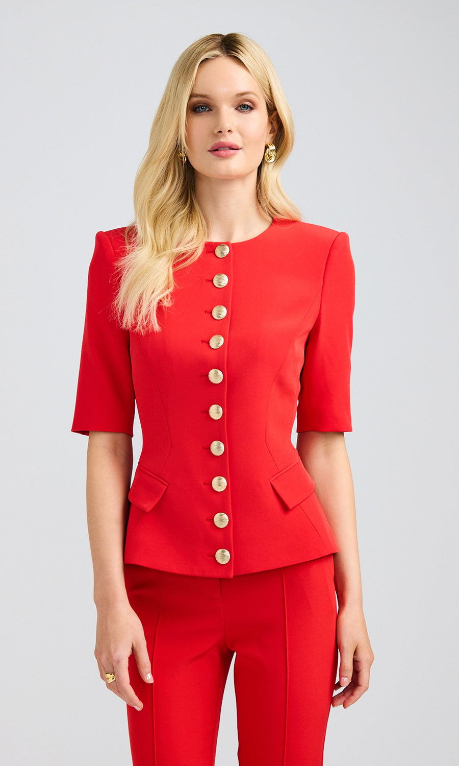 Blonde model wearing a red lightweight crepe jacket with short sleeves and gold buttons, emphasizing the suit's elegance