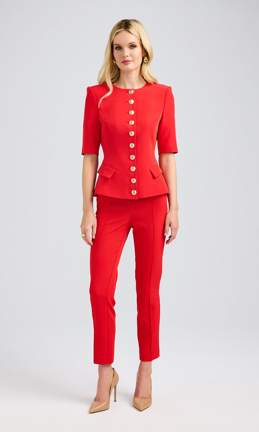 Full-body view of a blonde model in a red lightweight suit with short sleeves and gold buttons, looking stylish and confident.