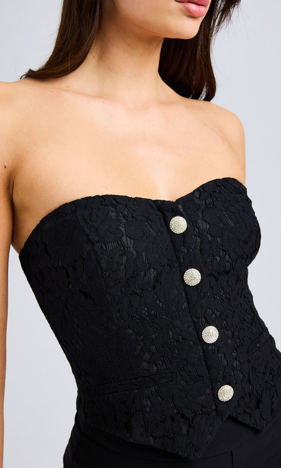 Close-up of the black vestier showcasing the intricate lace detailing and shimmering crystal button accents.