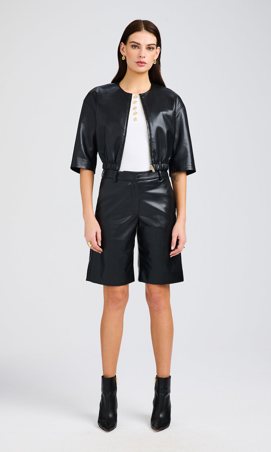 Full-body view of the model wearing the vegan leather bomber, styled with a white top and black shorts.