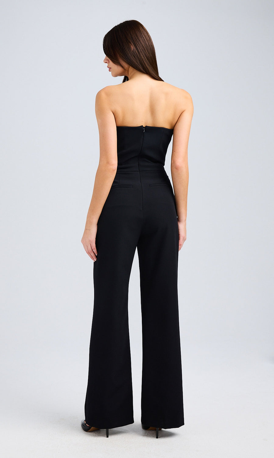 Rear view of the black strapless jumpsuit, showcasing a fitted bodice and wide-leg design with a concealed zipper closure