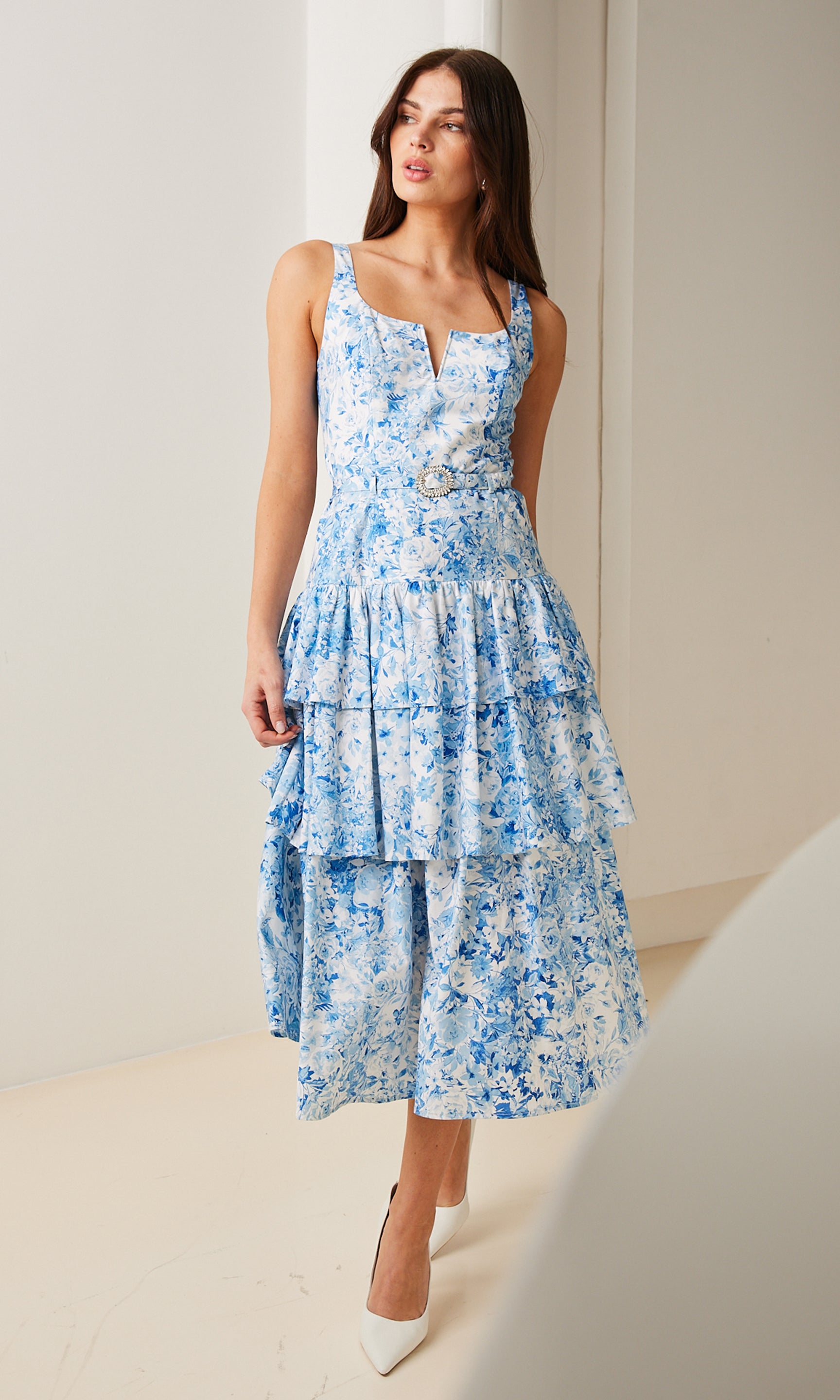 model wearing a white and blue floral dress paired with white heels