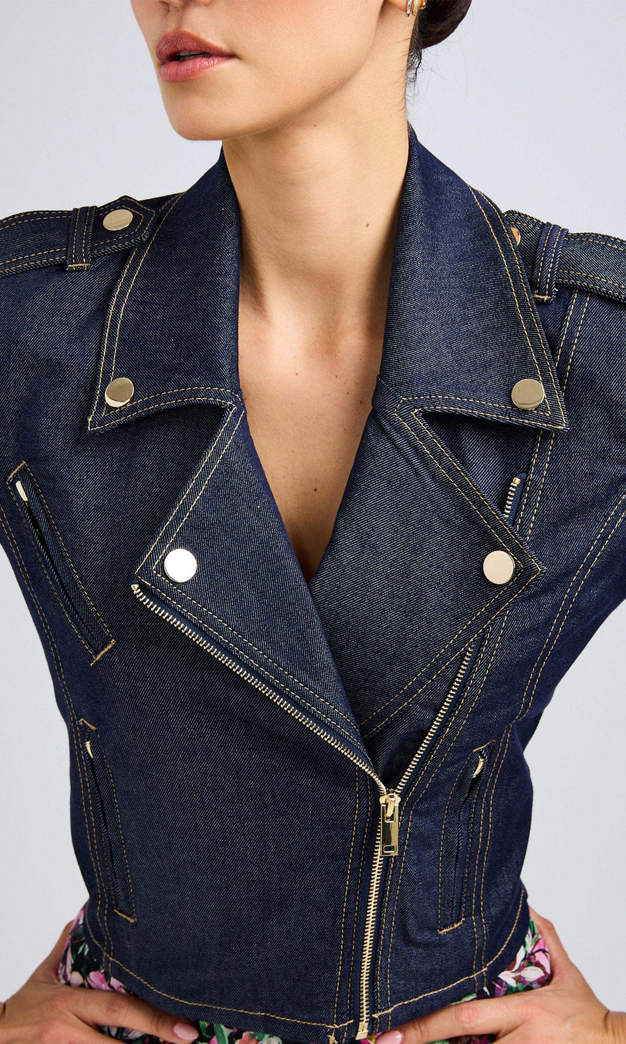 Close-up of a woman wearing a dark denim moto jacket with zippers.