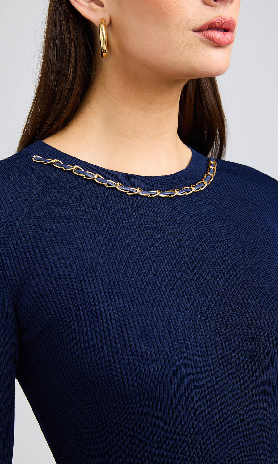 close up image of model wearing blue sweater with chain around neck