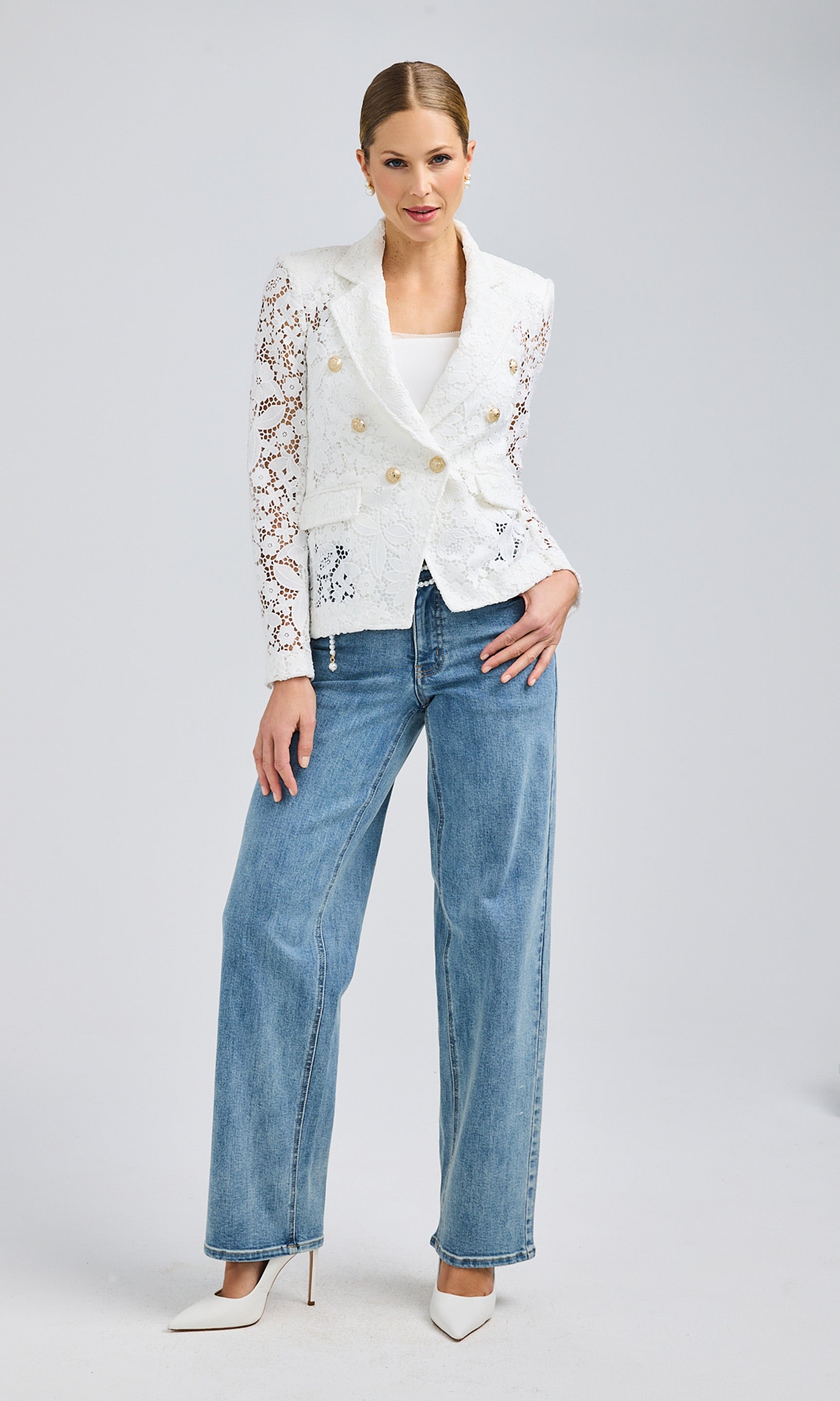 Full-body front view of the model showcasing the white lace blazer paired with relaxed-fit denim jeans and white heels.