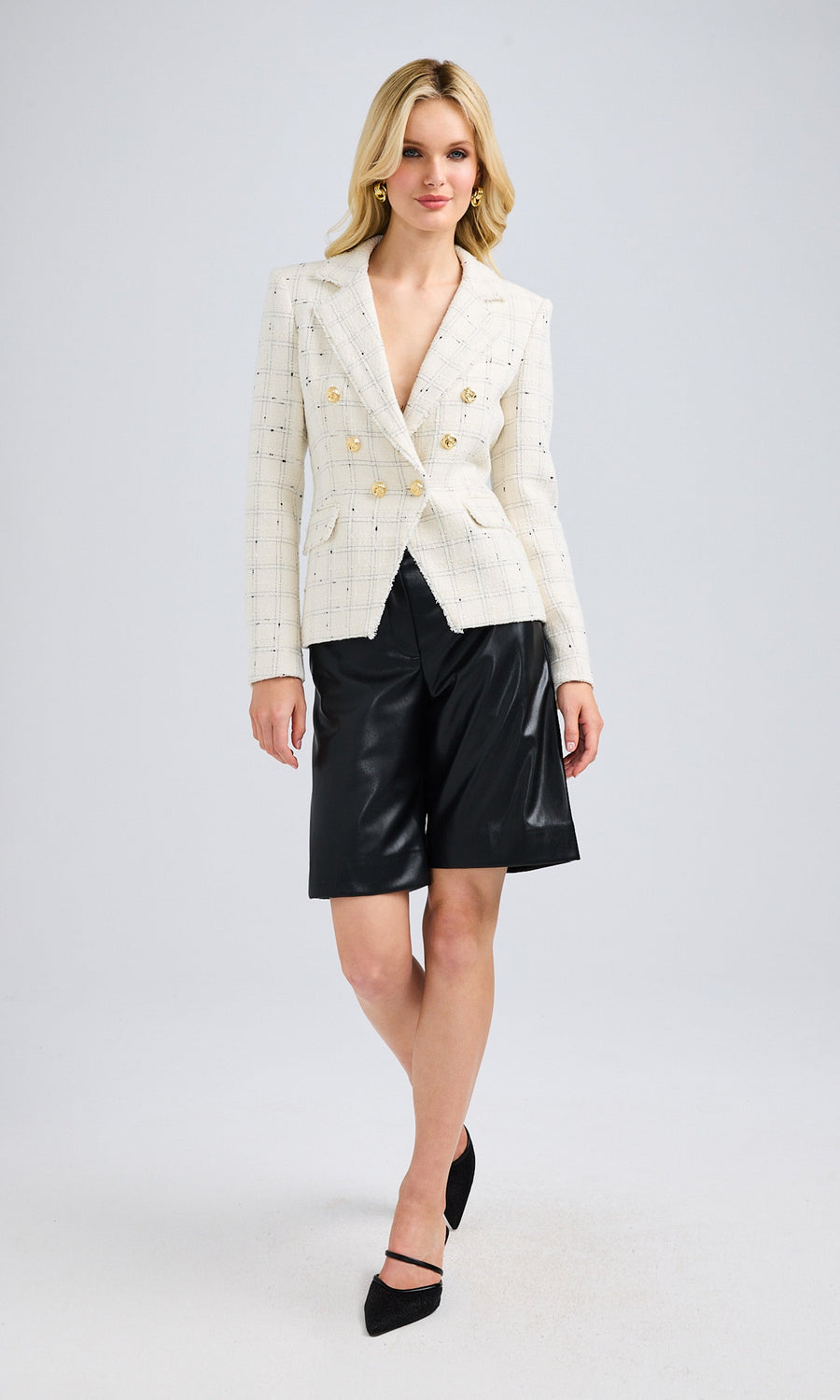 Model wearing a tailored white tweed jacket styled with black leather pants