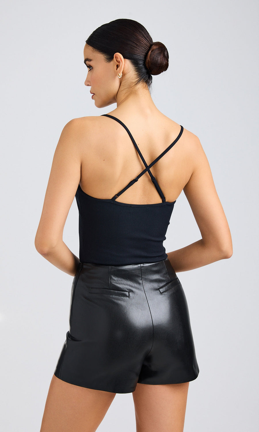 Back view of black lace cami showing thin straps and fitted bodice, styled with vegan leather shorts.