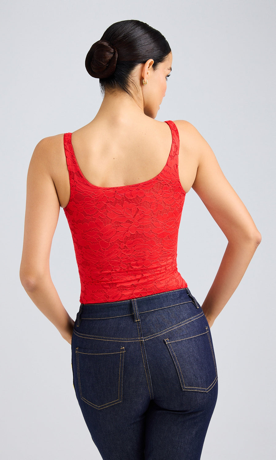  A Rear view of a woman wearing jeans and red Gigi Lace Top, exuding style and confidence in her casual attire.