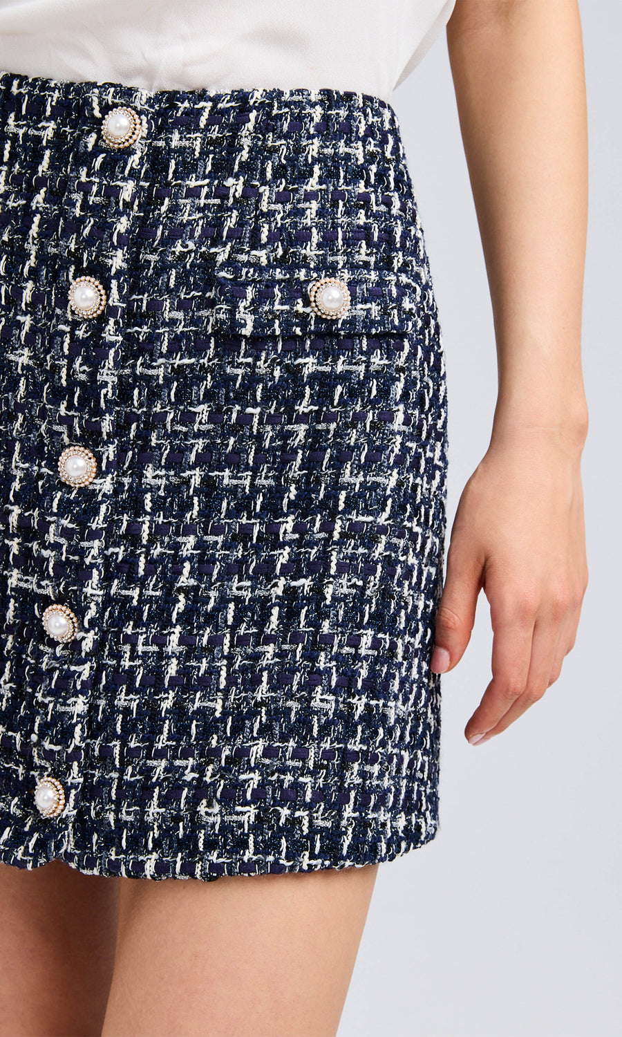 Close-up of the tweed skirt highlighting the halo pearl button detail and textured fabric.