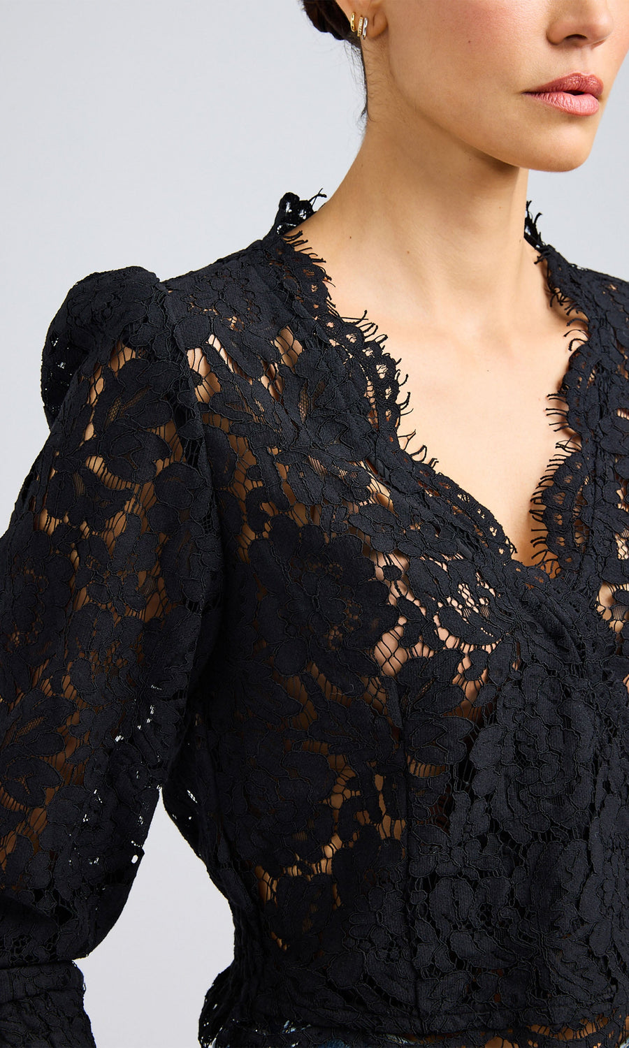 Close-up of a woman wearing a black long-sleeve lace blouse with a deep v-neck.