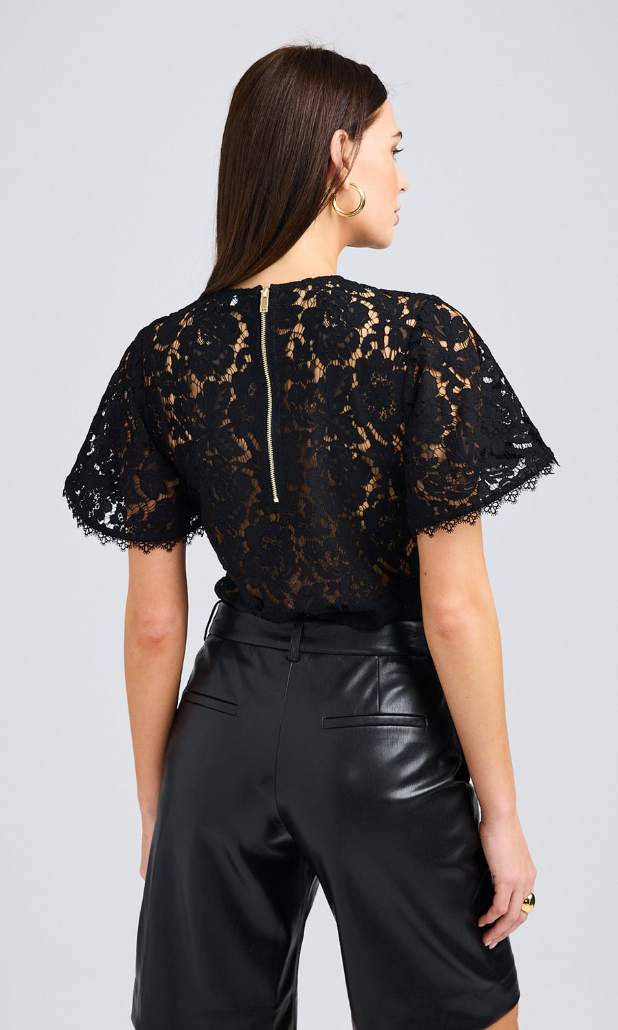 Side view of the model showcasing the fit and back detailing of the black lace vestier design.