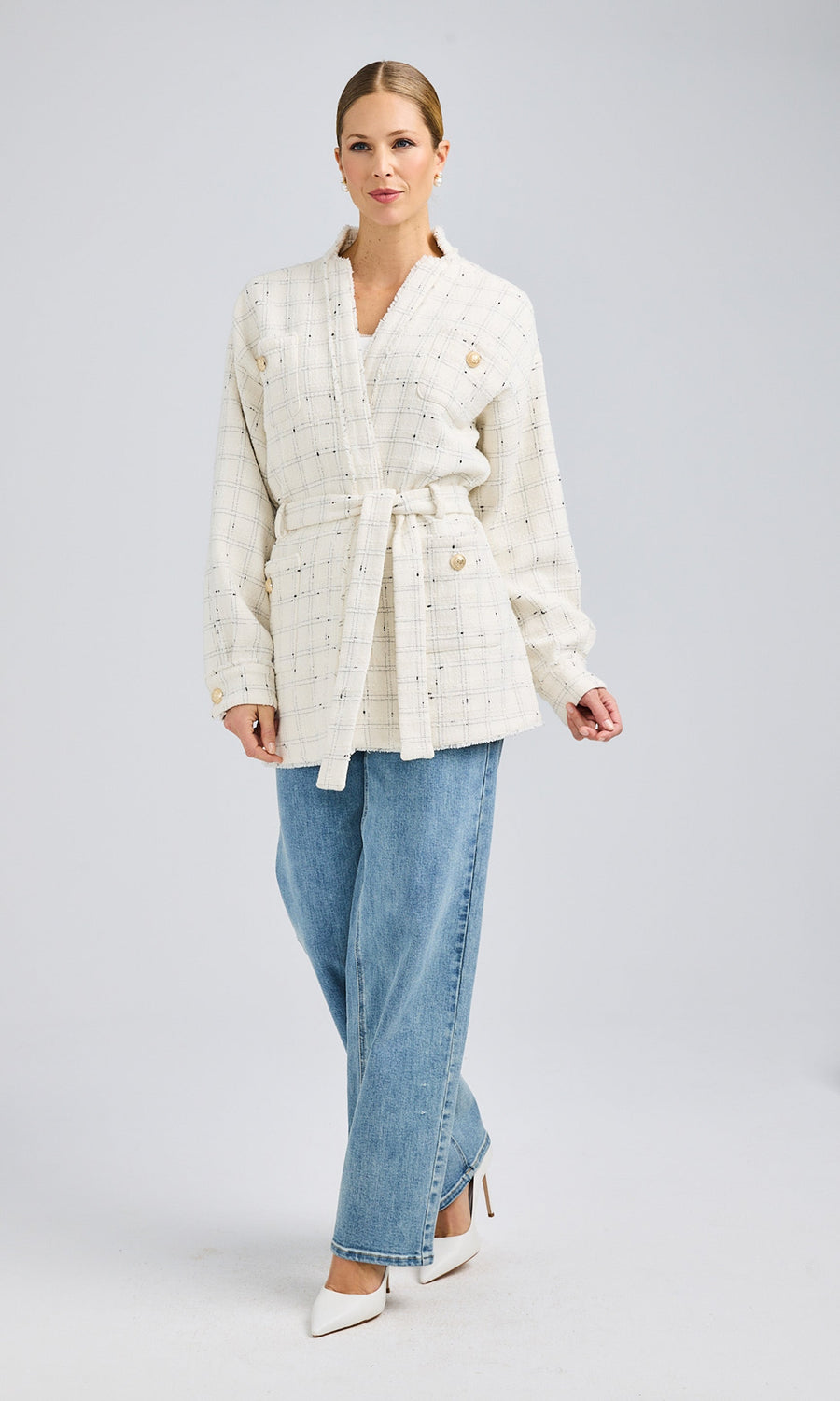 Side angle emphasizing the jacket's longline cut, tailored structure, and shimmering gold button details, paired with a crisp white top and casual jeans.