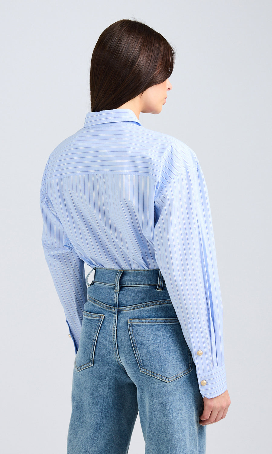 Side angle of the model in the light blue shirt, emphasizing the soft cotton fabric and relaxed silhouette.