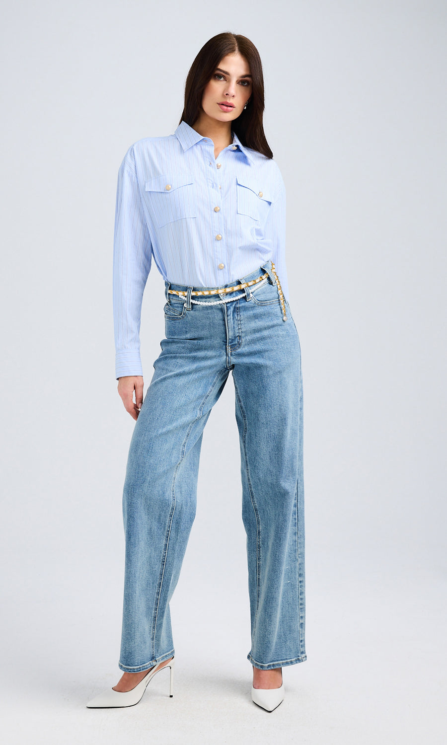 Full-body view of the model wearing the light blue shirt and high-waisted denim jeans, showing the overall styling and fit.