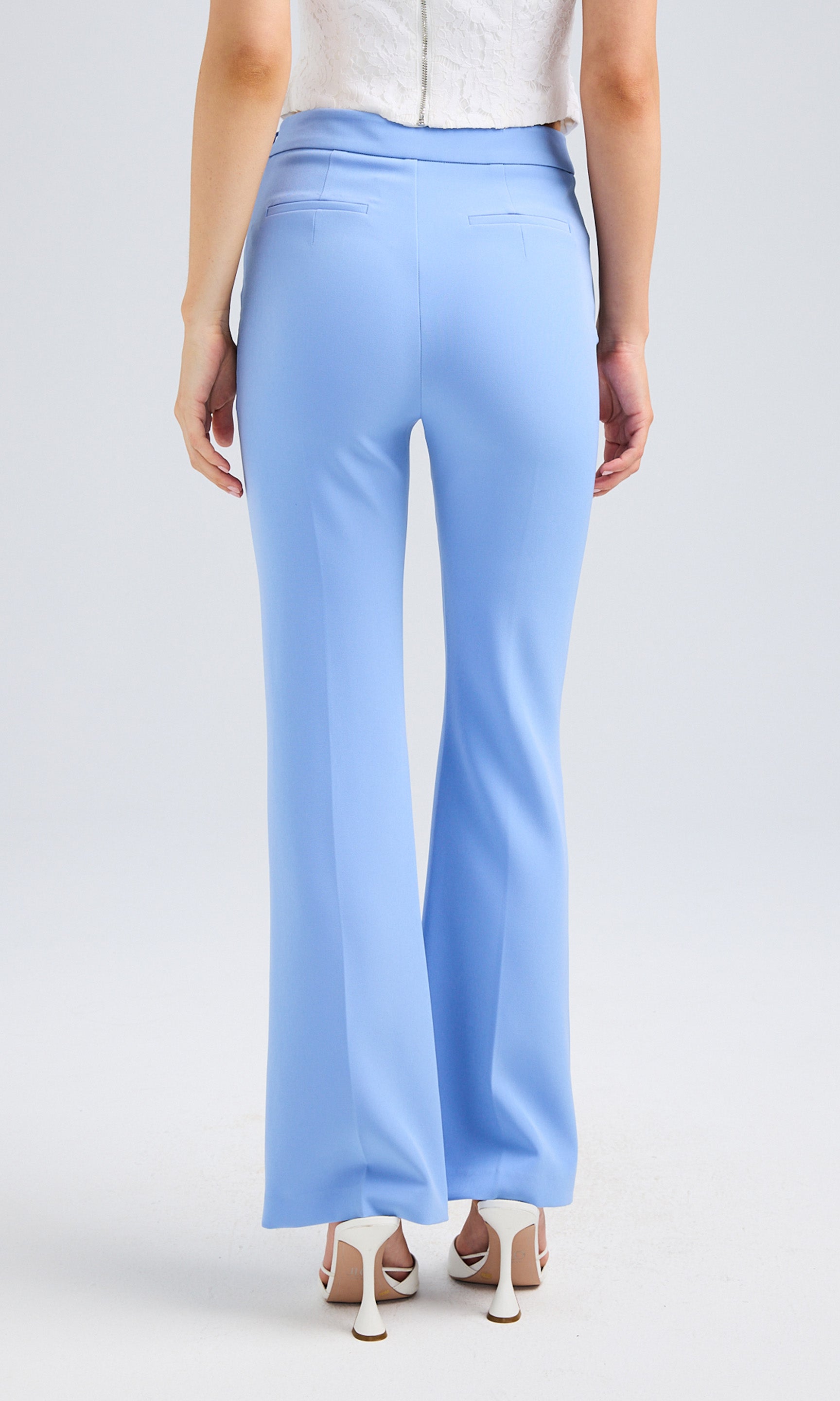 Rear view of a blonde model in blue crepe pants, highlighting her fashionable outfit from behind.