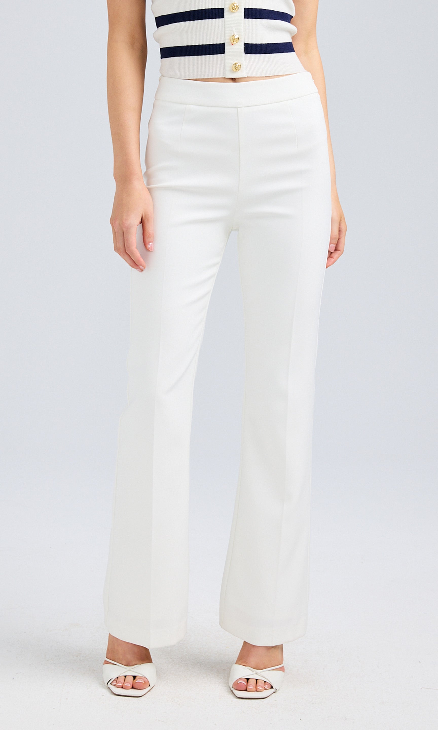 Front view of the white high-waisted pants, styled with a striped tank top.