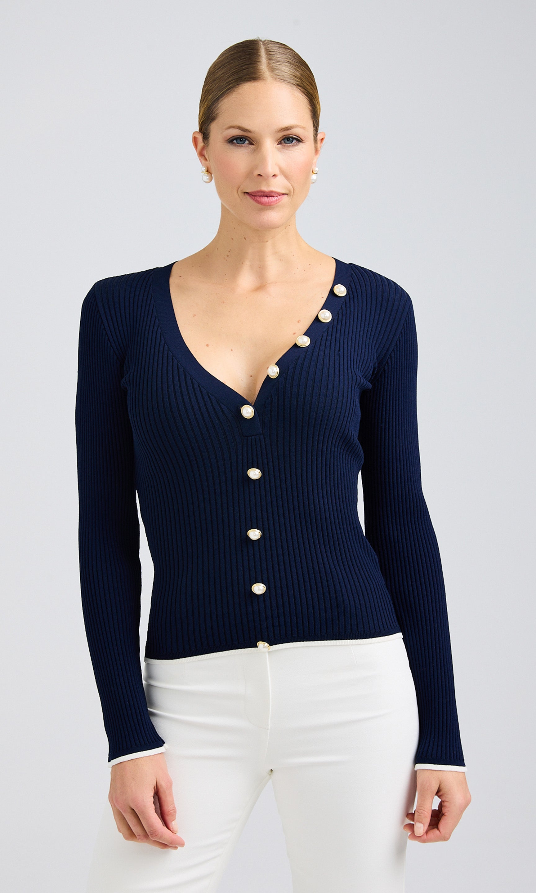 Navy cardigan sweater in rib knit, adorned with pearl buttons for a chic look.