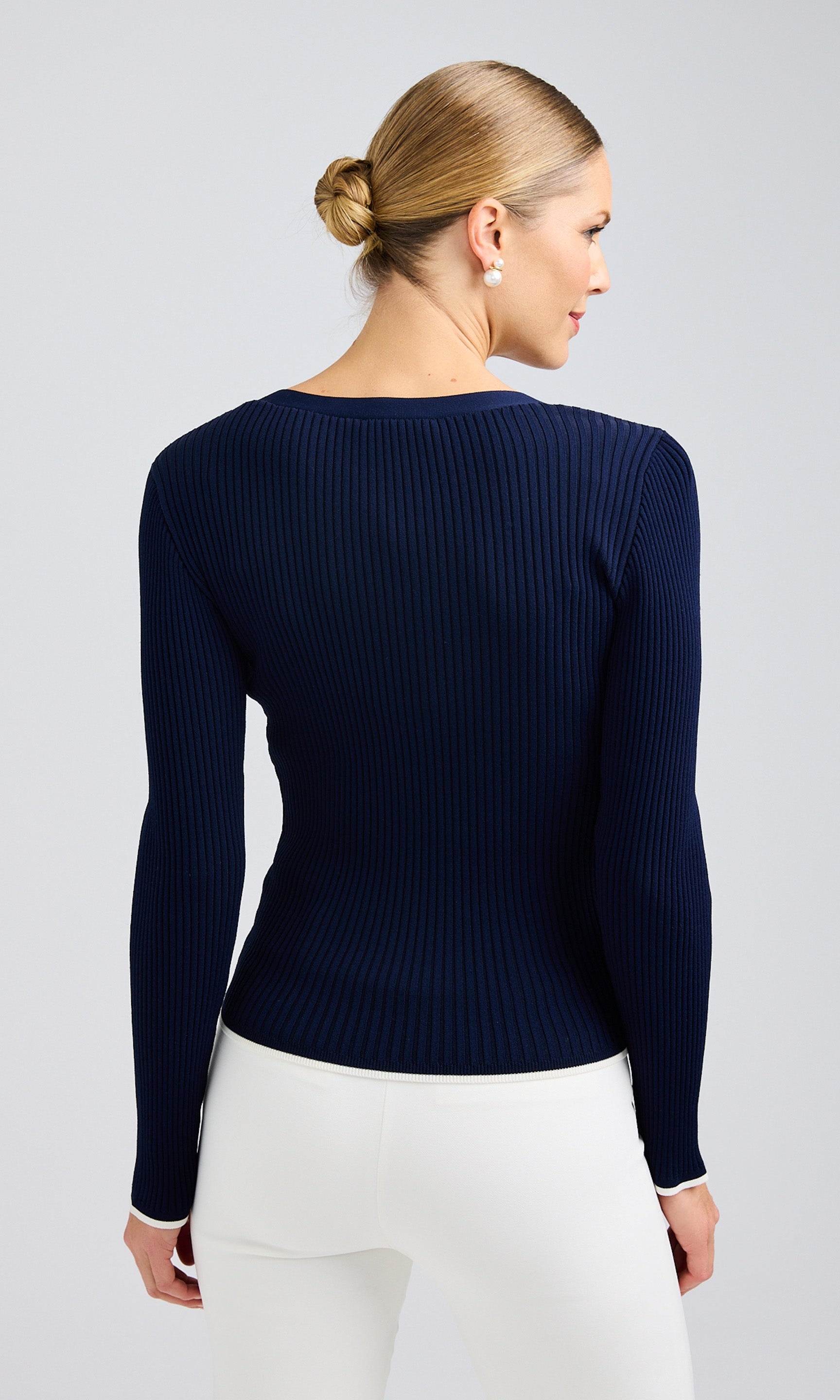 A Rear look at the navy blue ribbed Renata cardigan with white details and pearl buttons.