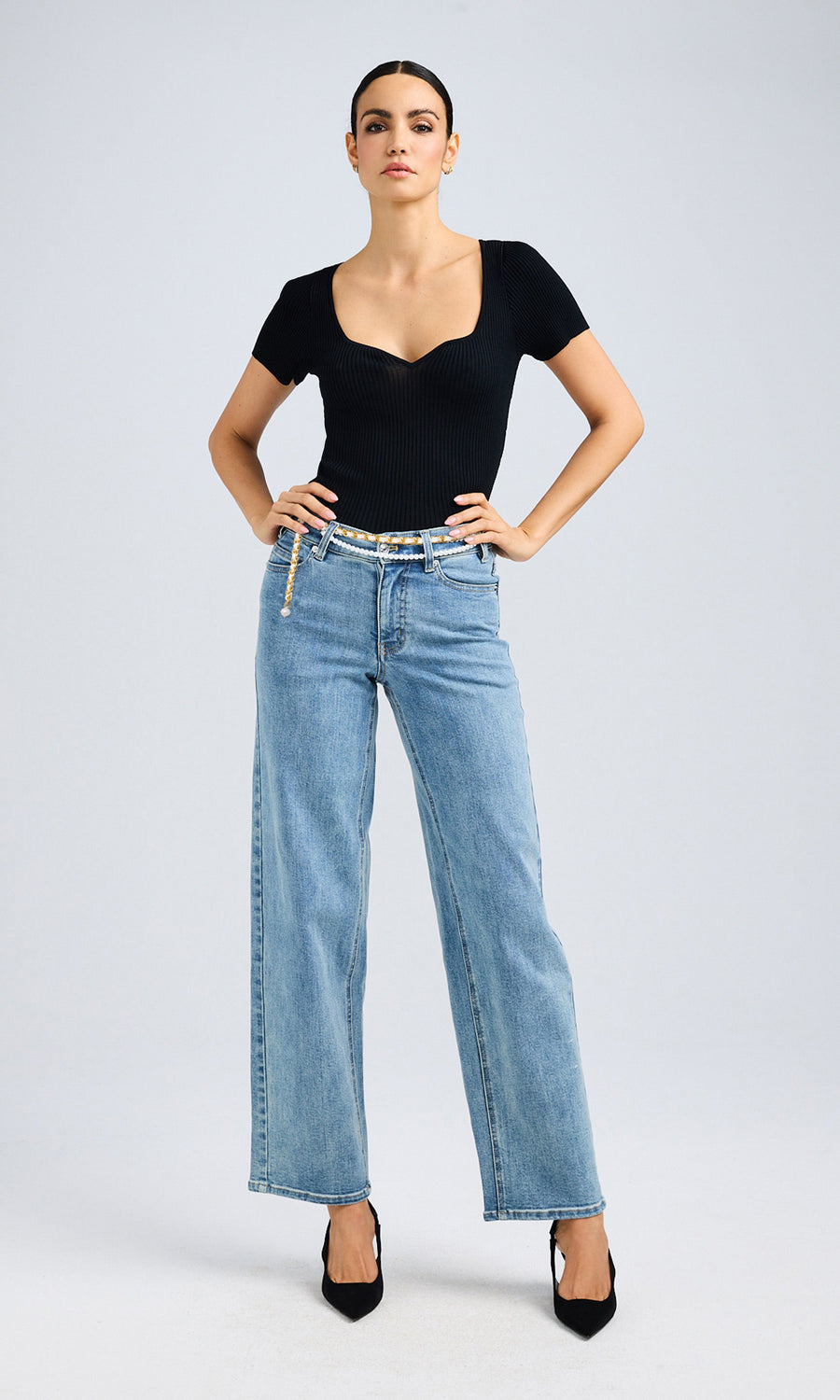 Full-body view of dark hair model dressed in a black top and wide-leg jeans, highlighting a trendy and relaxed look.