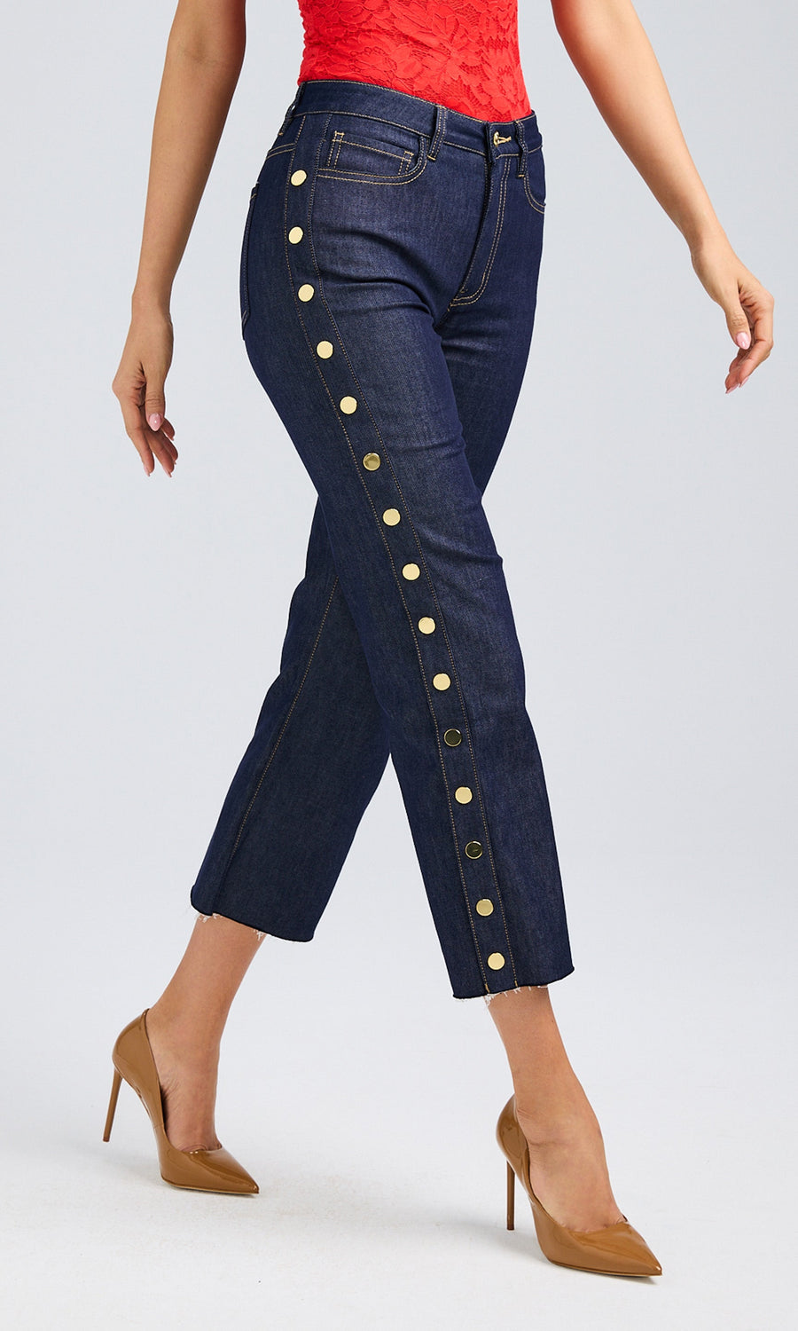 Side view of a woman in dark denim high-rise jeans featuring shiny golden buttons, highlighting her trendy outfit.