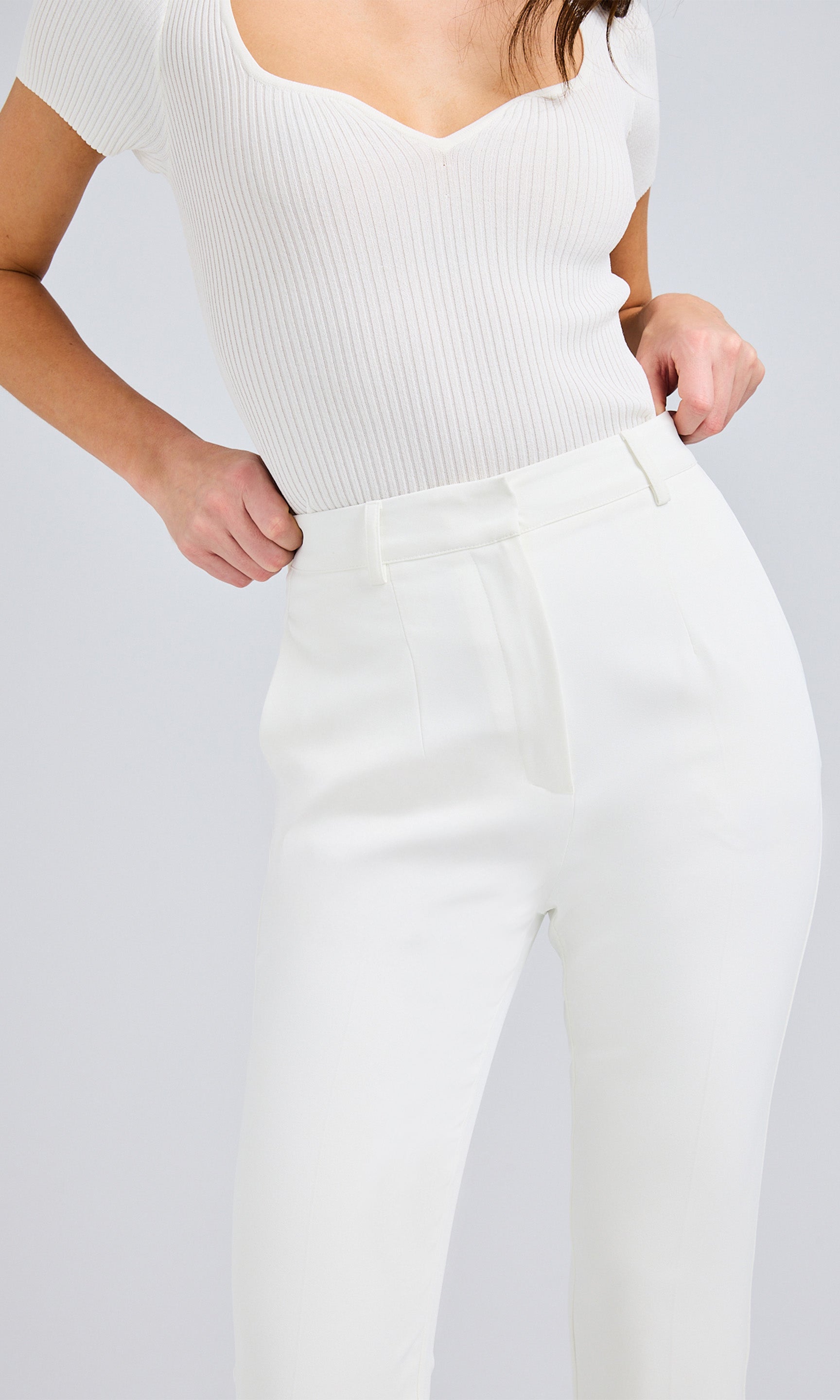 Close up of white slim-fit pants highlighting the sleek silhouette and functional side pockets.