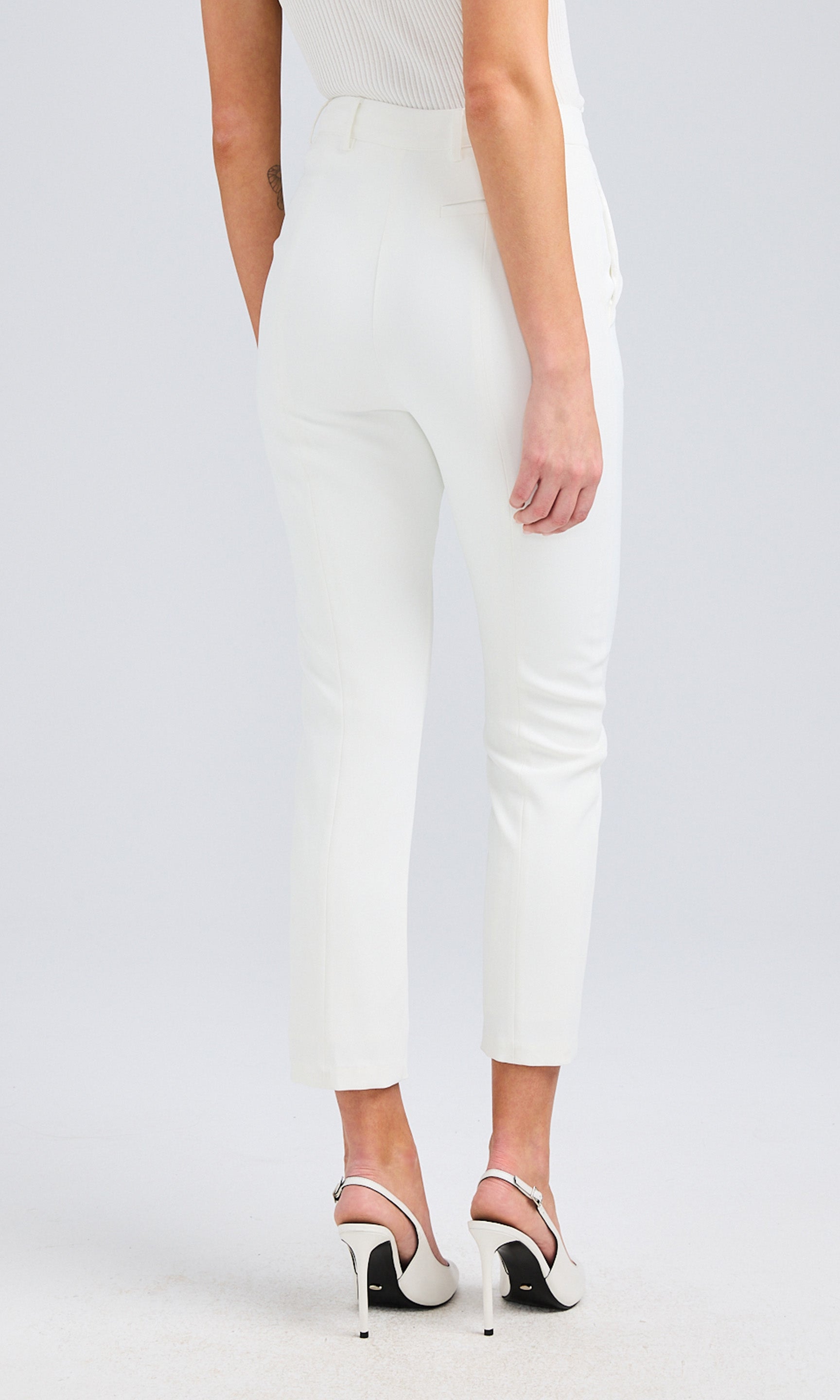 Rear view of white slim-fit pants, showing the non-functional back pocket details and tailored fit.