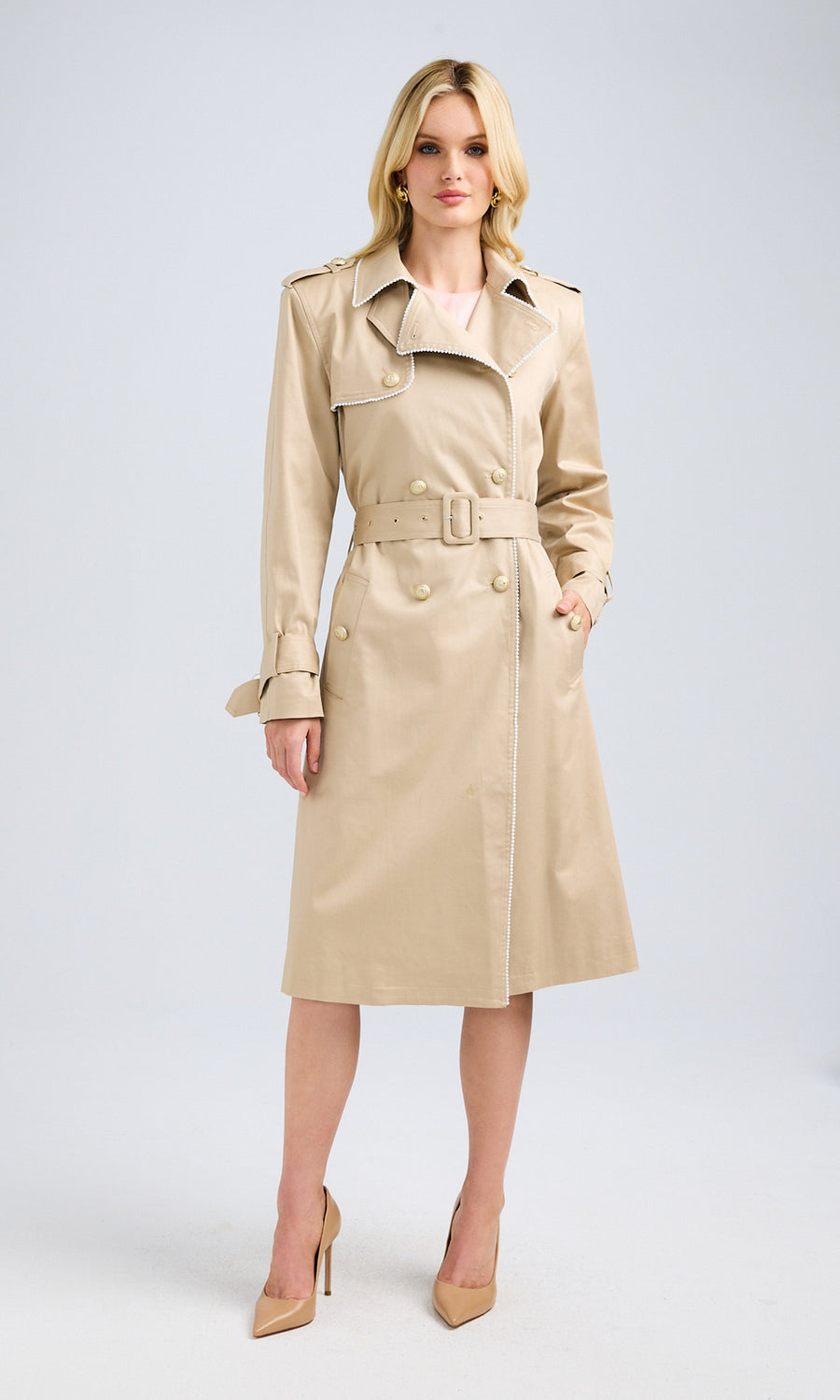 Front view of a model wearing a pearl beige trench coat with a boyfriend fit and functional pockets.