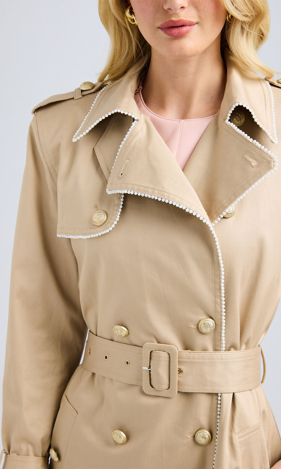 Close-up of the trench coat highlighting the laurel wreath shield shank button and collar detailing.