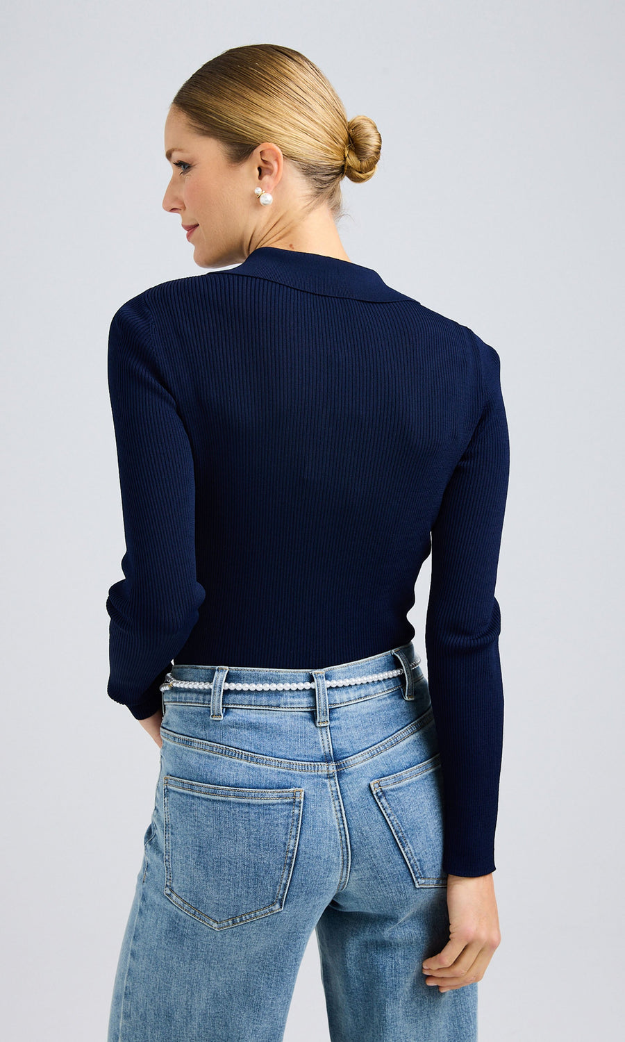 Rear back view of a woman in jeans and a navy sweater, showcasing a casual outfit.